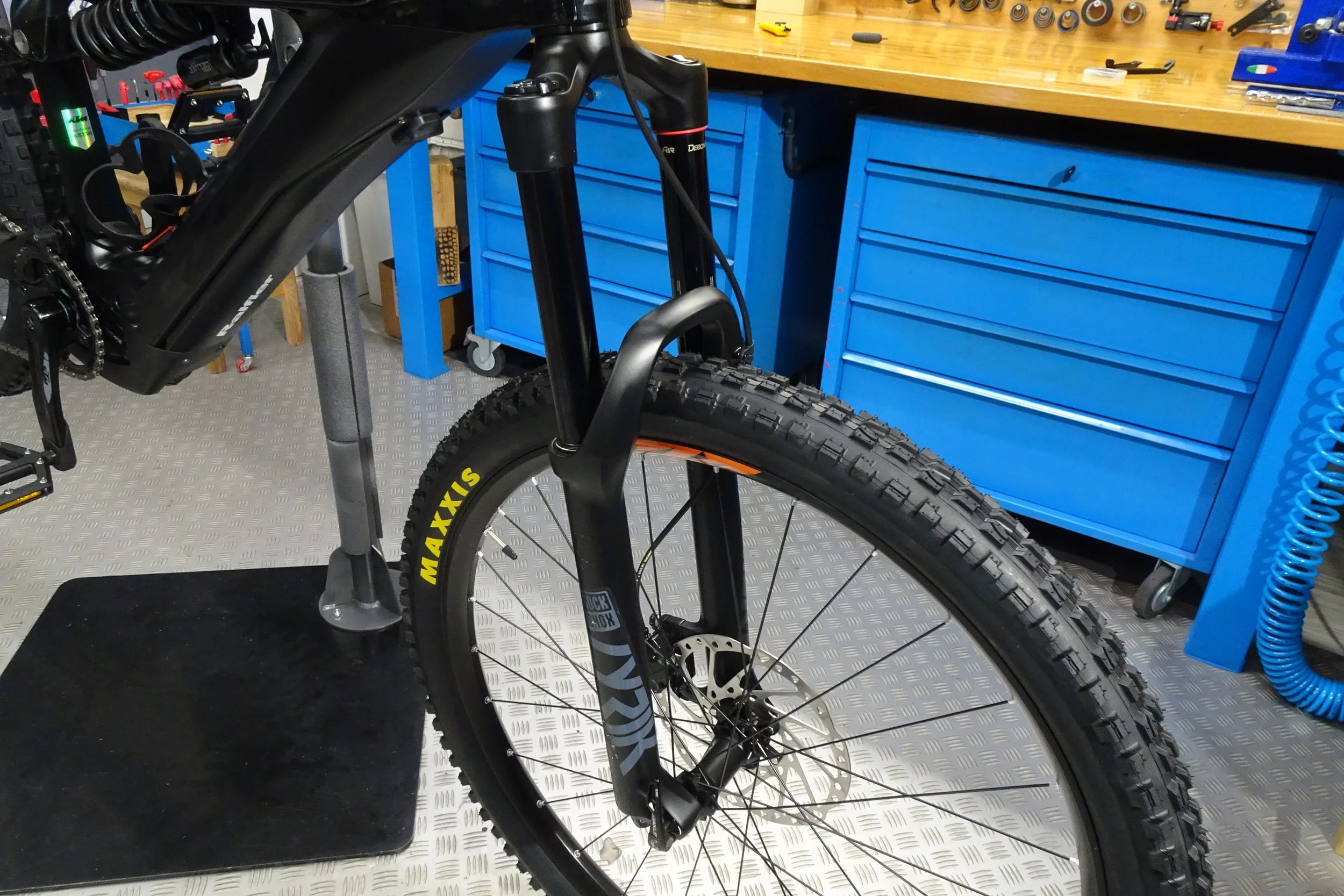 Monta una bicicletta su un supporto da officina in un garage con banchina di lavoro blu e cassetti.