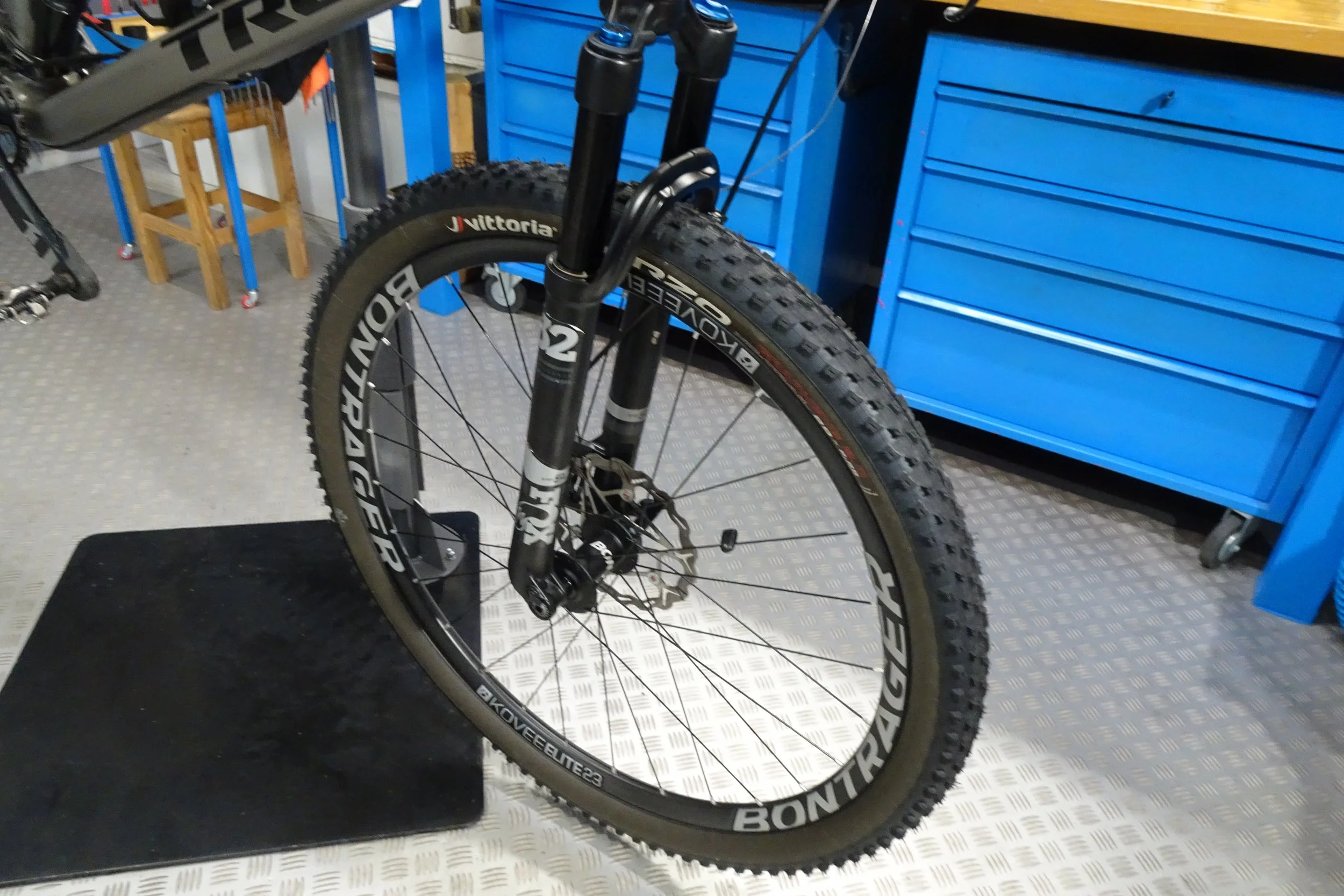 Bicicletta da mountain bike in un garage con arredi blu e un pavimento in metallo.