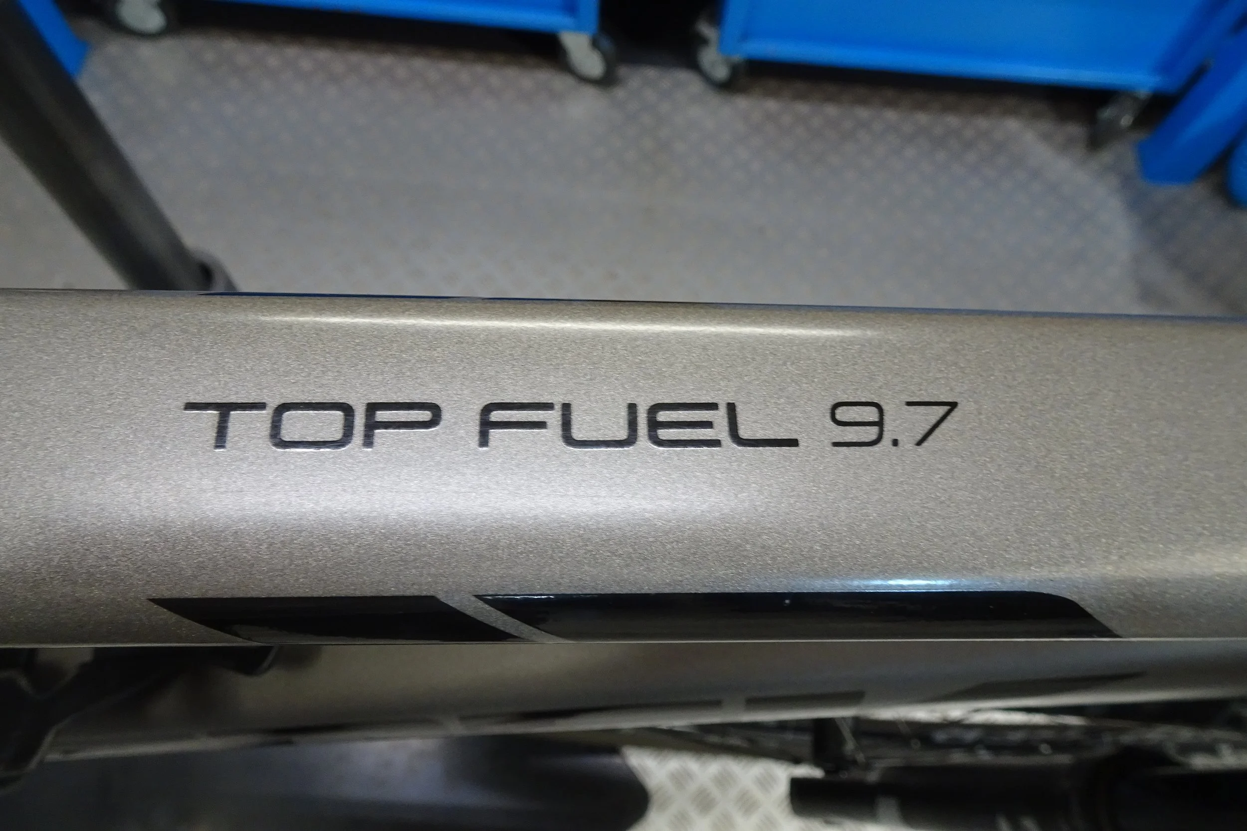 Un'etichetta con scritto "TOP FUEL 9.7" su un oggetto metallicato, probabilmente una parte di veicolo o equipaggiamento.