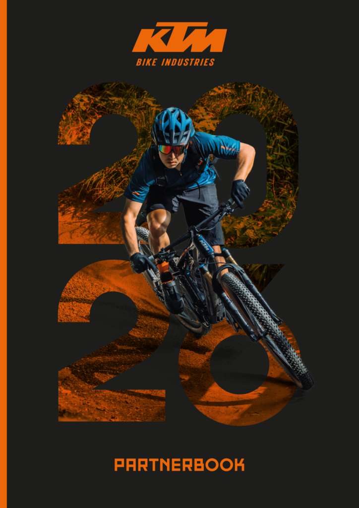 Copertina di un libro che mostra un ciclista su mountain bike che scia su un sentiero di terra, con il testo 'KTM Bike Industries 2020 Partnerbook' in evidenza.