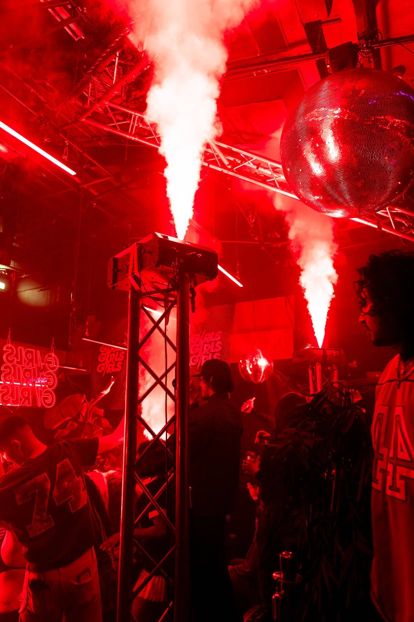 Een bruisend feest met een discobal, rode verlichting en mensen die dansen en plezier maken.