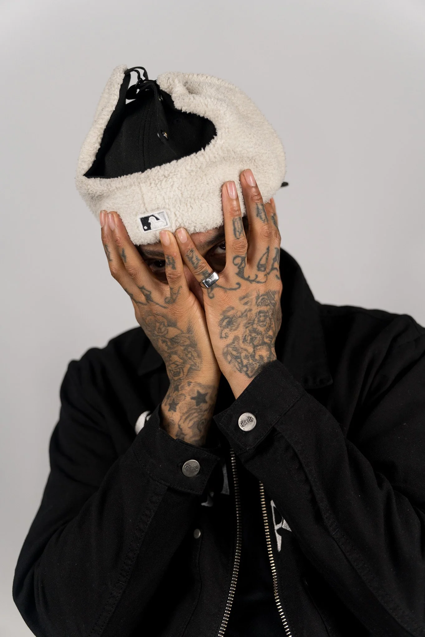 Man met tattoos die een teddy pet met baseballcap op zijn hoofd houdt en de nadruk op zijn tatoeages legt.