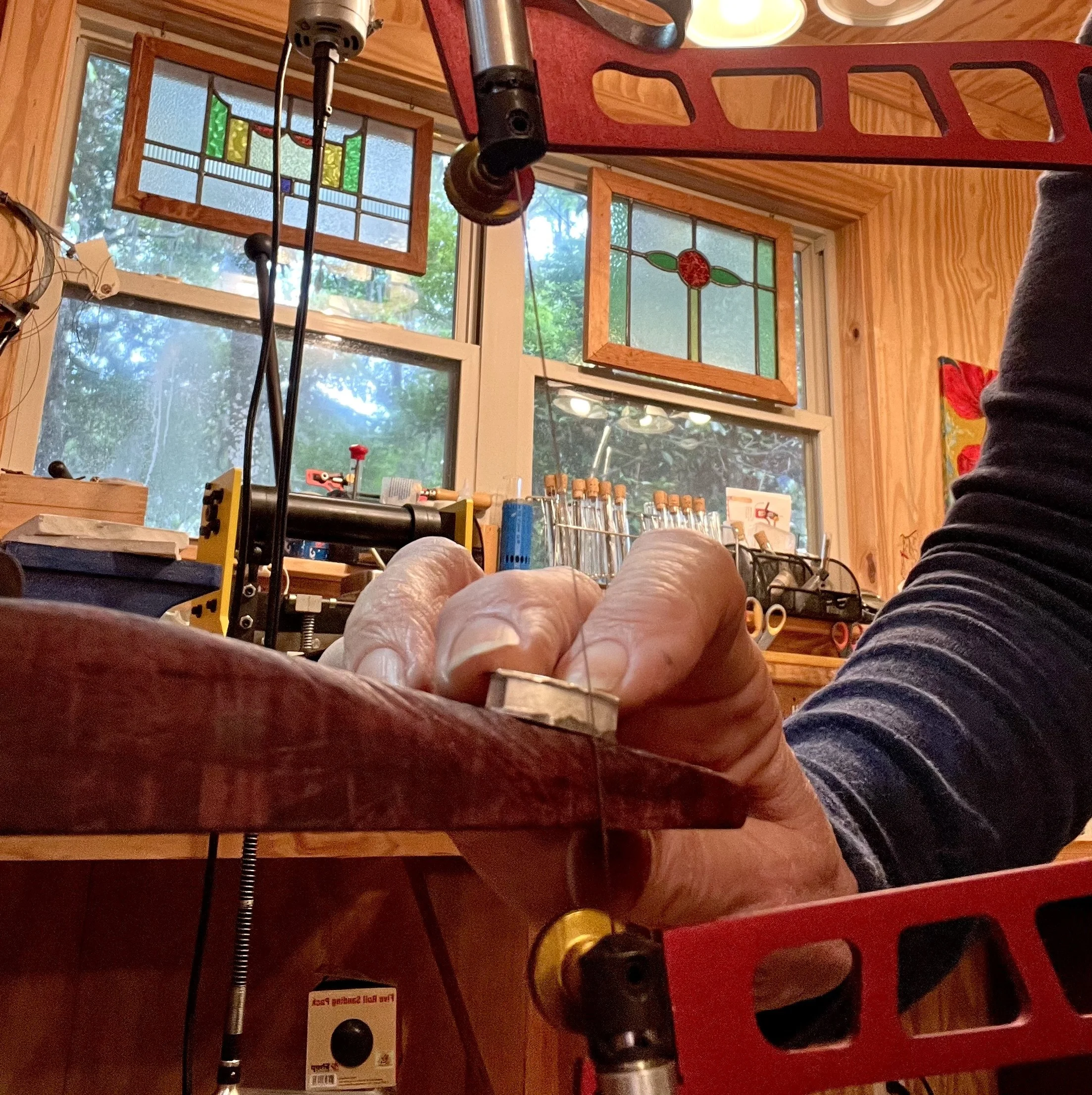 A red foam hockey game table with various hockey pieces and a hockey stick attached to a spring, set inside a room with wooden paneling and stained glass windows.
