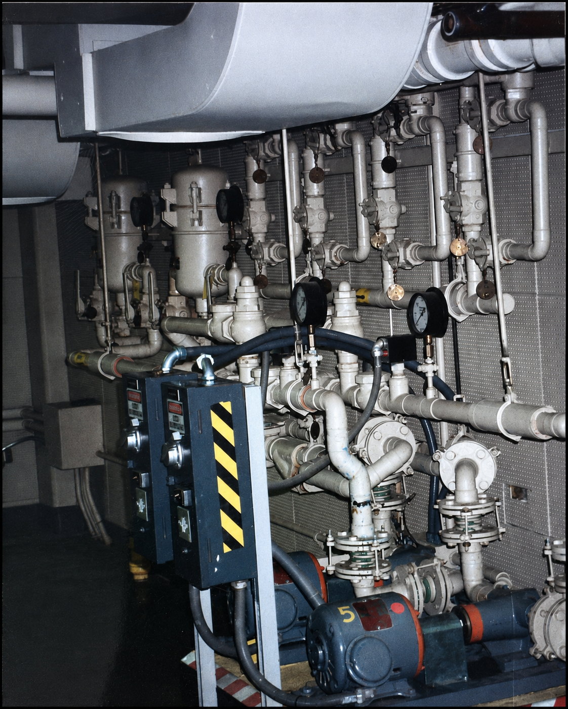 Industrial mechanical piping system with gauges, valves, and a motor.