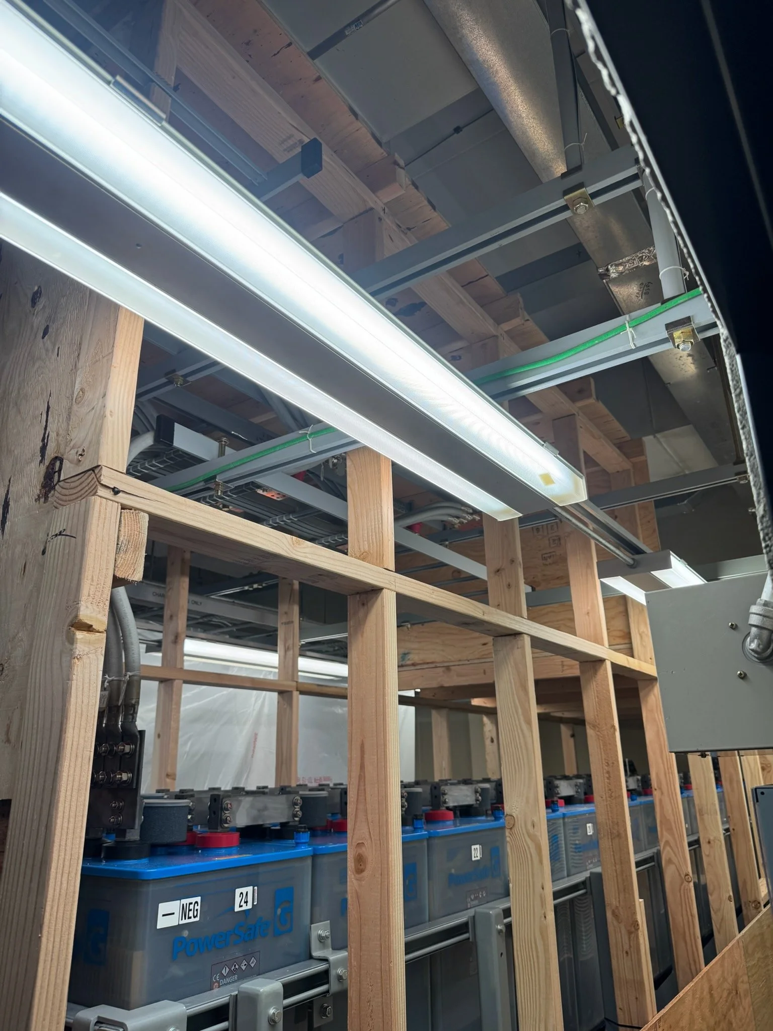 Electrical batteries installed within a wooden framing structure, with visible wiring and electrical components.