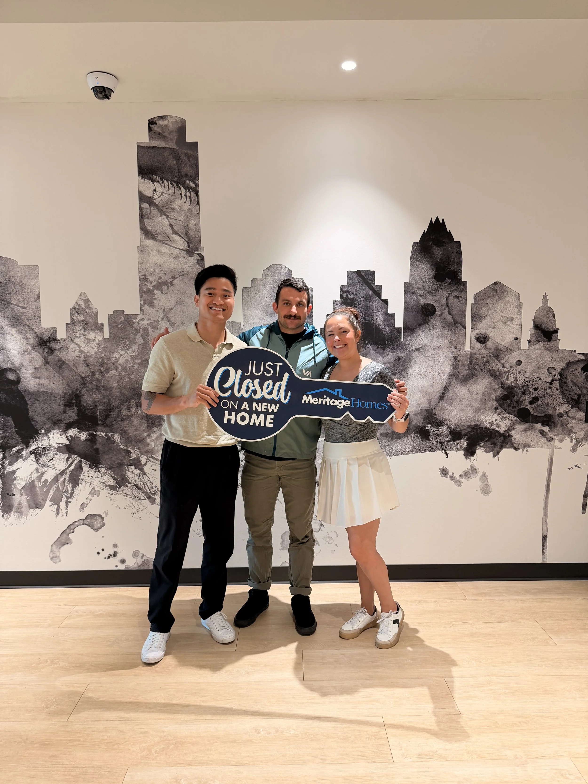 Kien with buyers holding a Just Closed on a New Home key sign