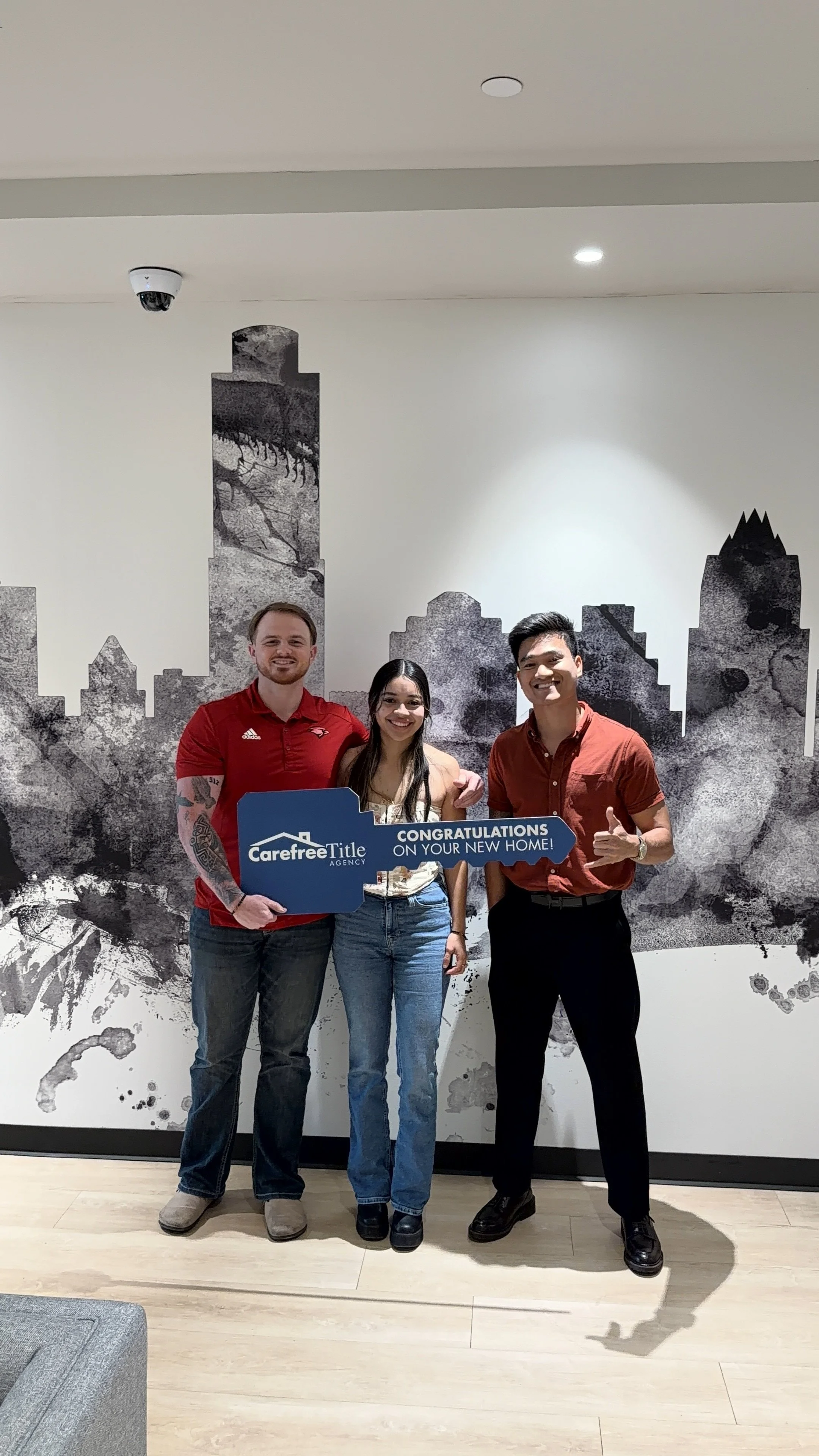 Kien with clients holding a Congratulations on your new home sign at their Austin closing