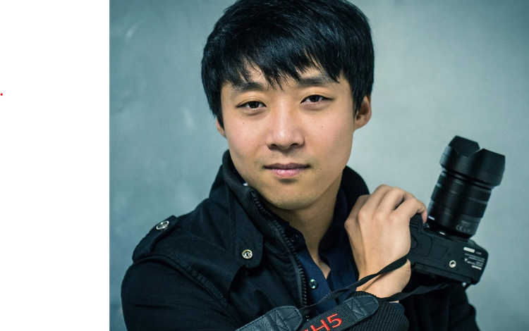 Portrait of a young man holding a DSLR camera with a telephoto lens