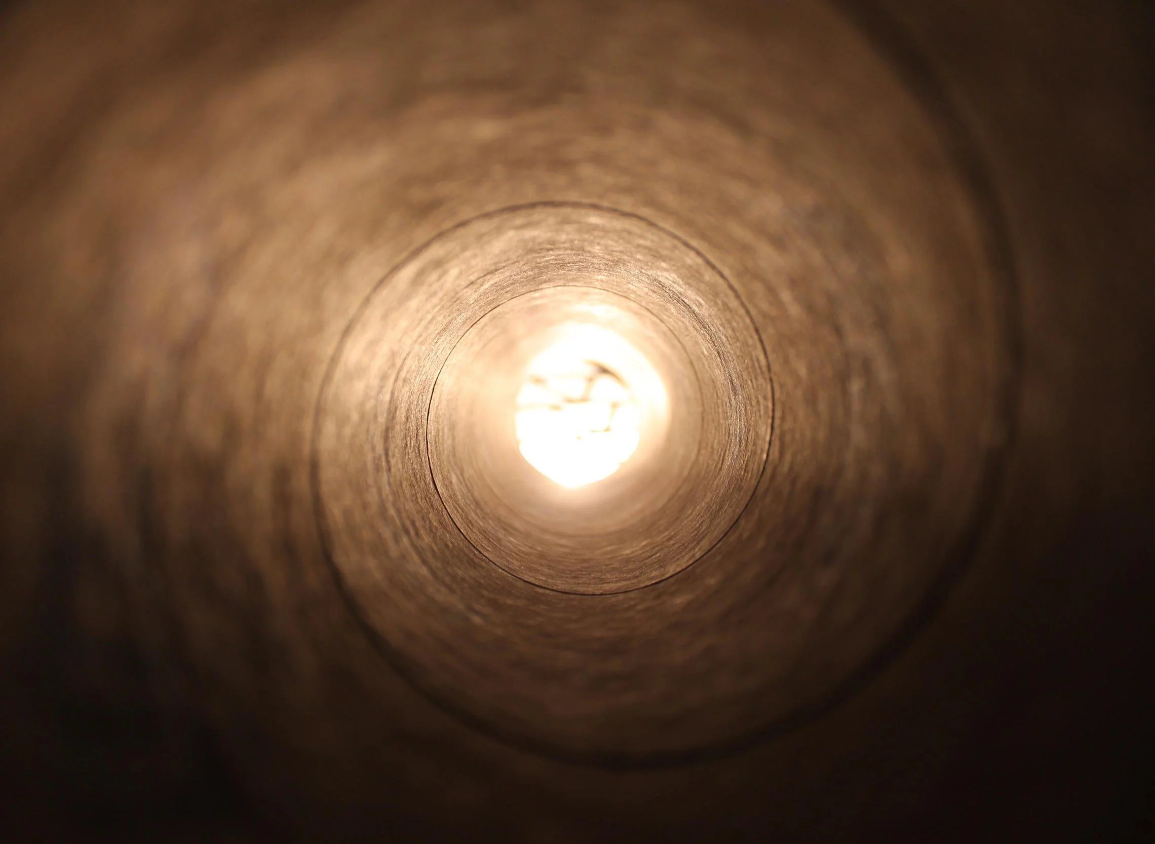 Looking down inside a cardboard tube towards the light at the end.