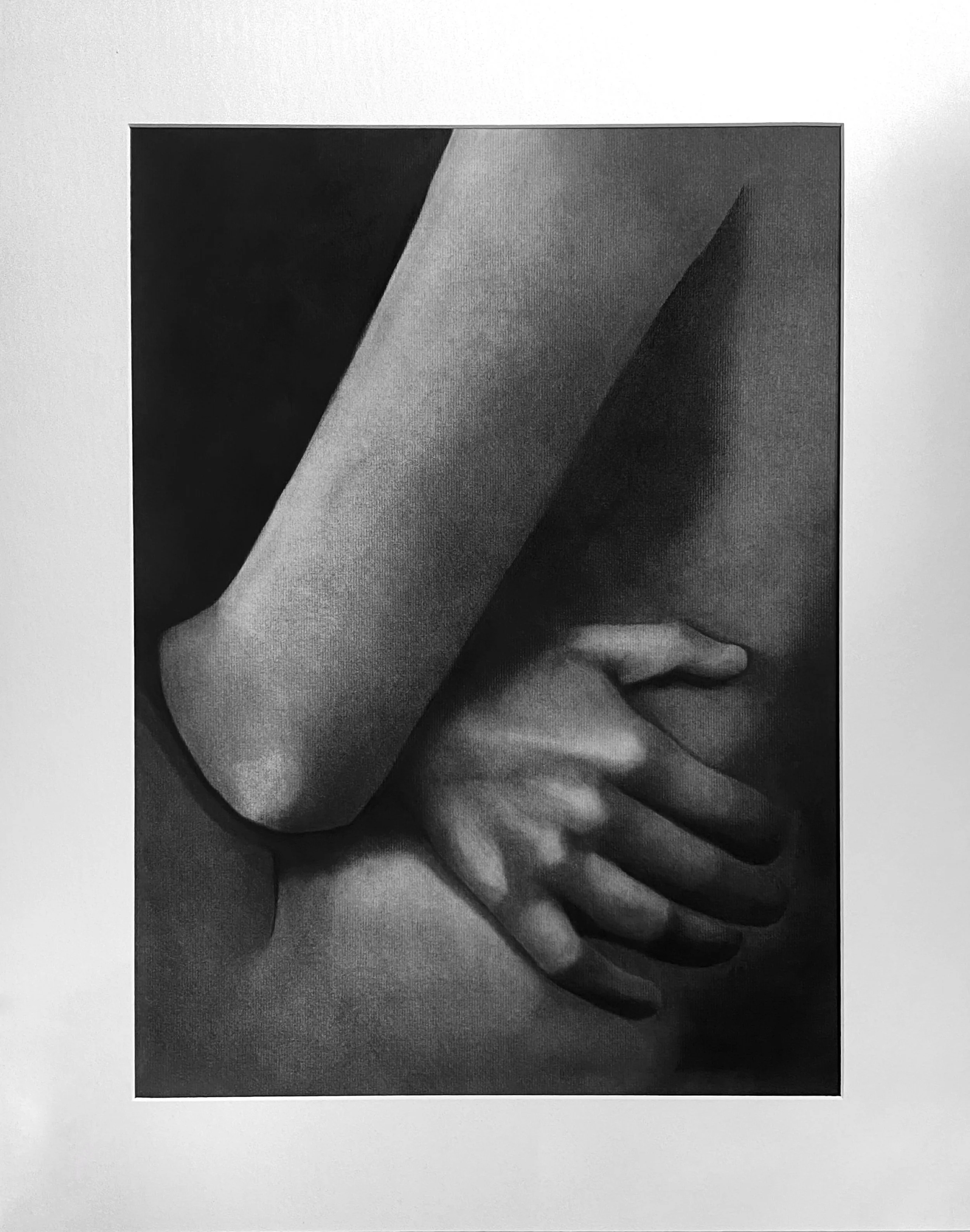 Black and white photograph of a person with their hand on their elbow, cropped to show only part of their arm and hand, with a plain background.