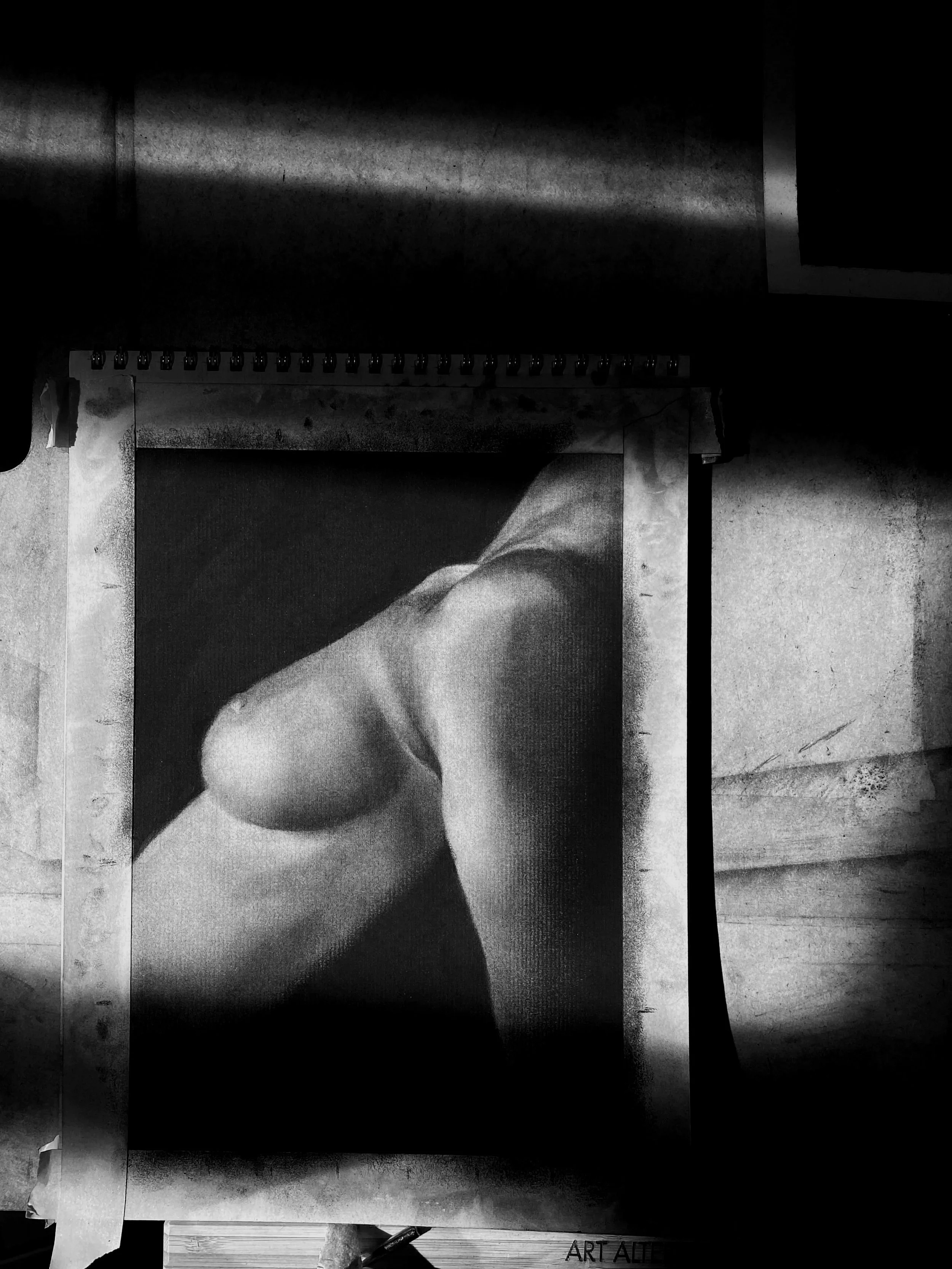 Black and white photo of a person with a focus on their shoulder and arm, sitting or leaning in a relaxed pose.