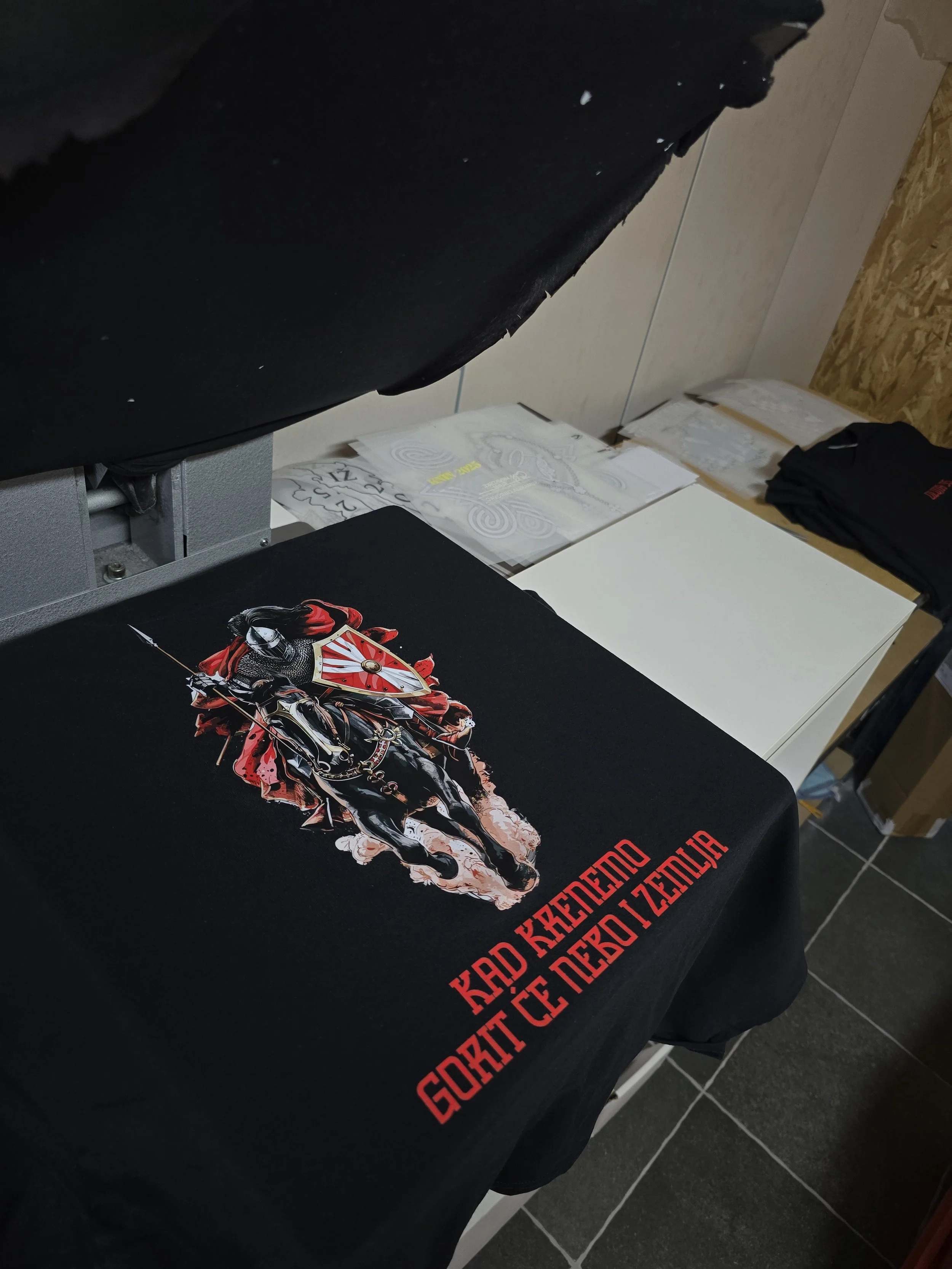 Black T-shirt featuring a graphic of a knight on horseback holding a lance, with red and white detailing, and text in red that reads 'Guerre Kércégou Zenobia'.