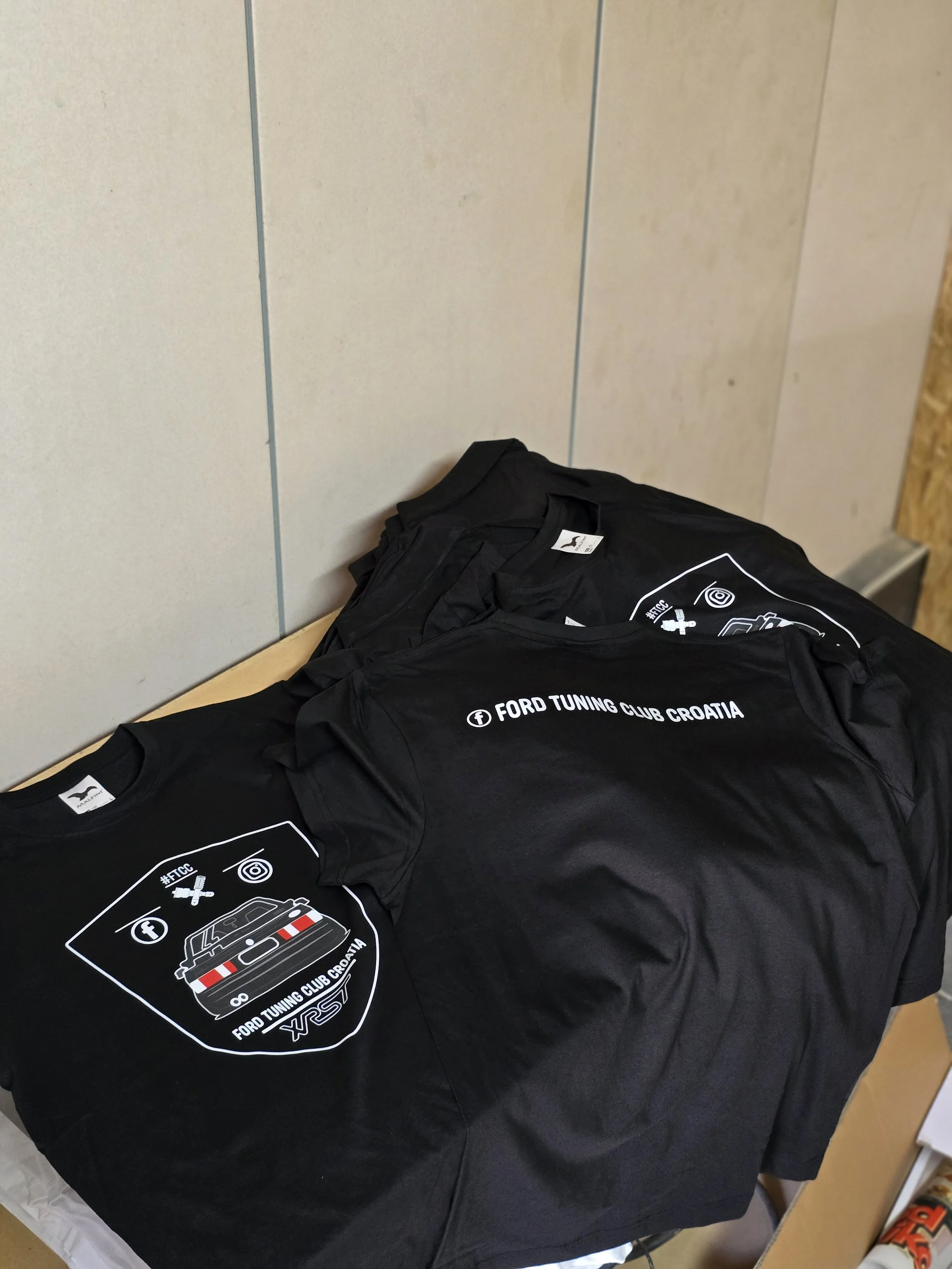 Black T-shirt with Ford Tuning Club Croatia logo, laying on a table.
