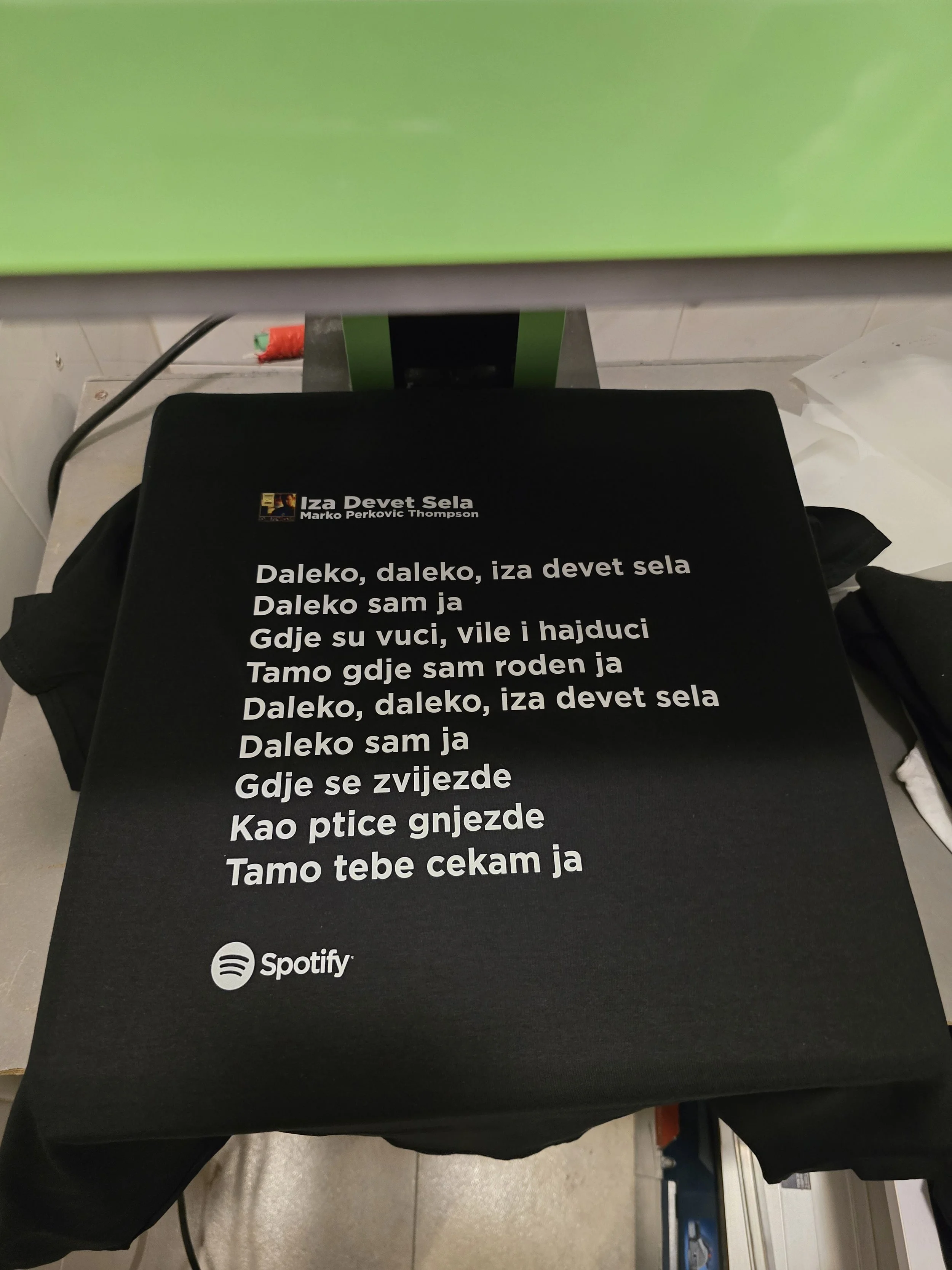 Black surface with white text of song lyrics in a language other than English, with a small Spotify logo at the bottom.