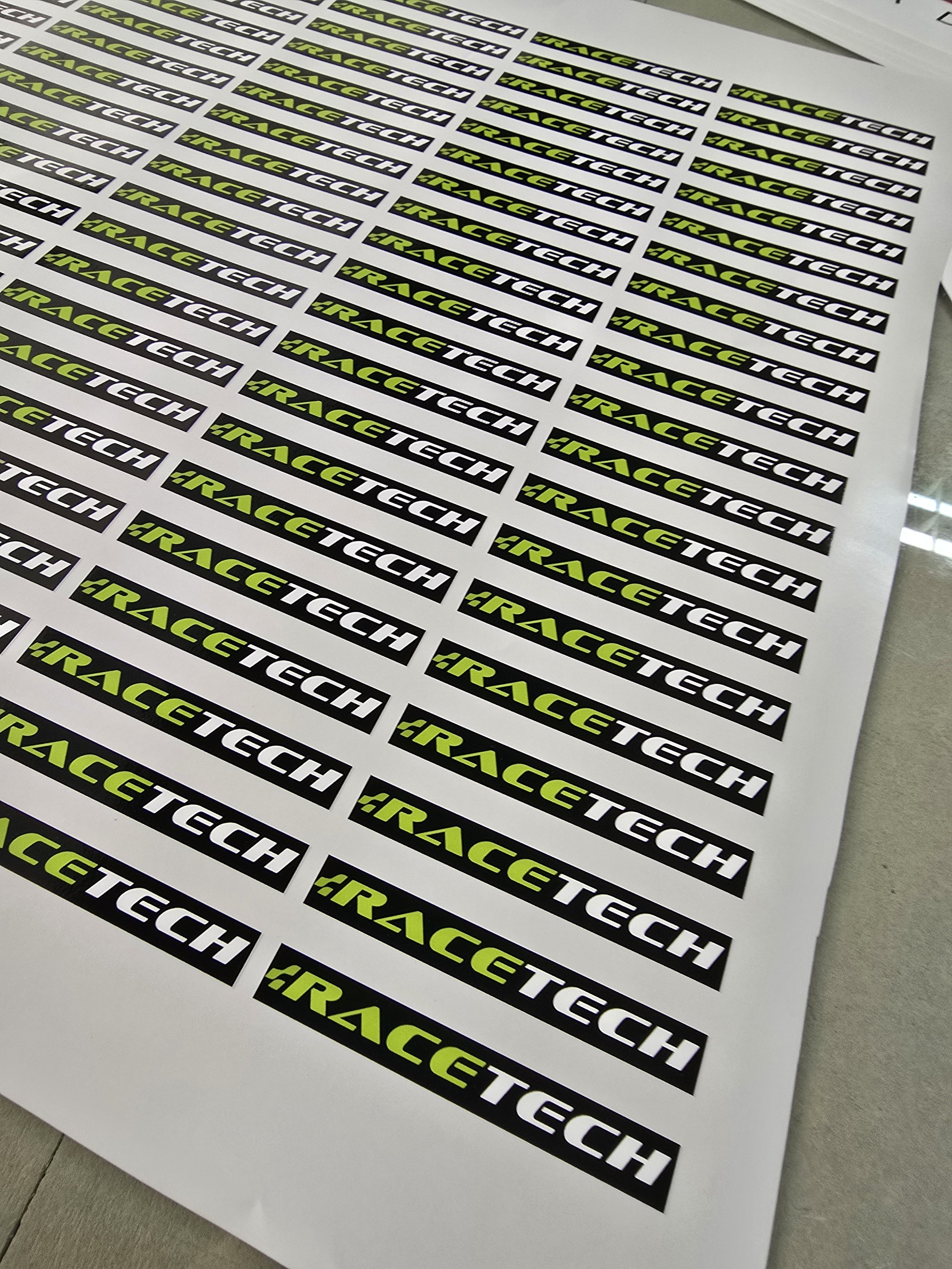 Rows of stickers with the text 'IRACE TECH' in black on a white background, with a bright green highlight on 'IR' in each sticker.