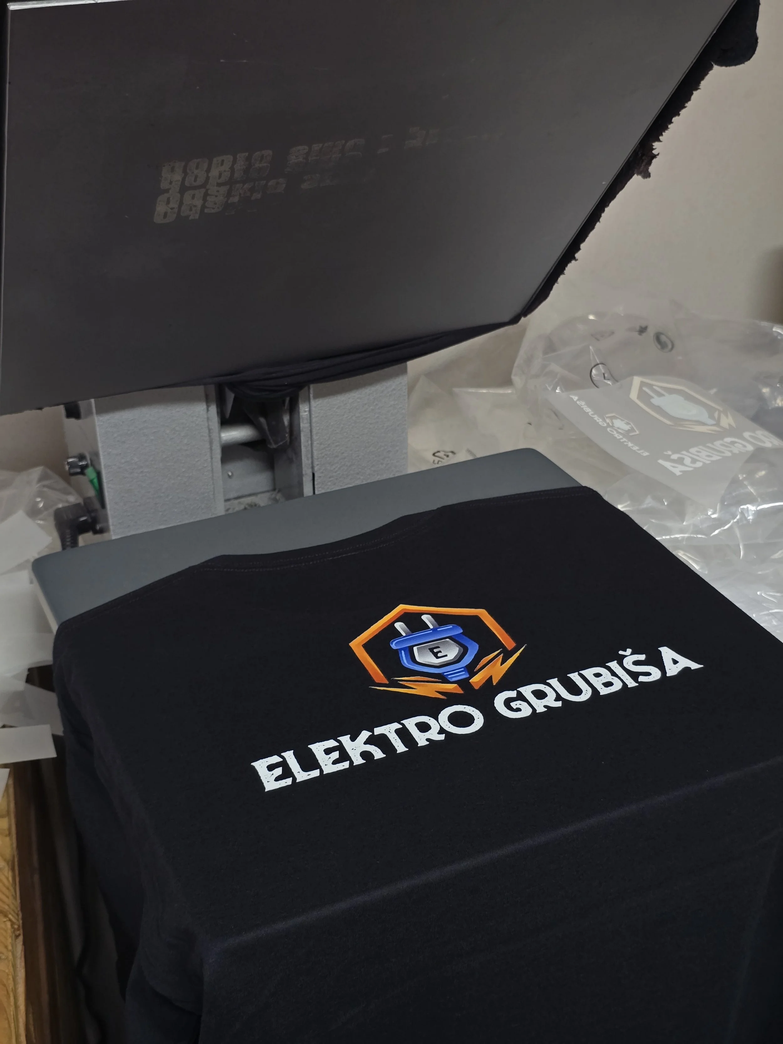 Black tablecloth with the Elektro Grubisa logo and text on it, placed in front of a computer monitor on a desk.