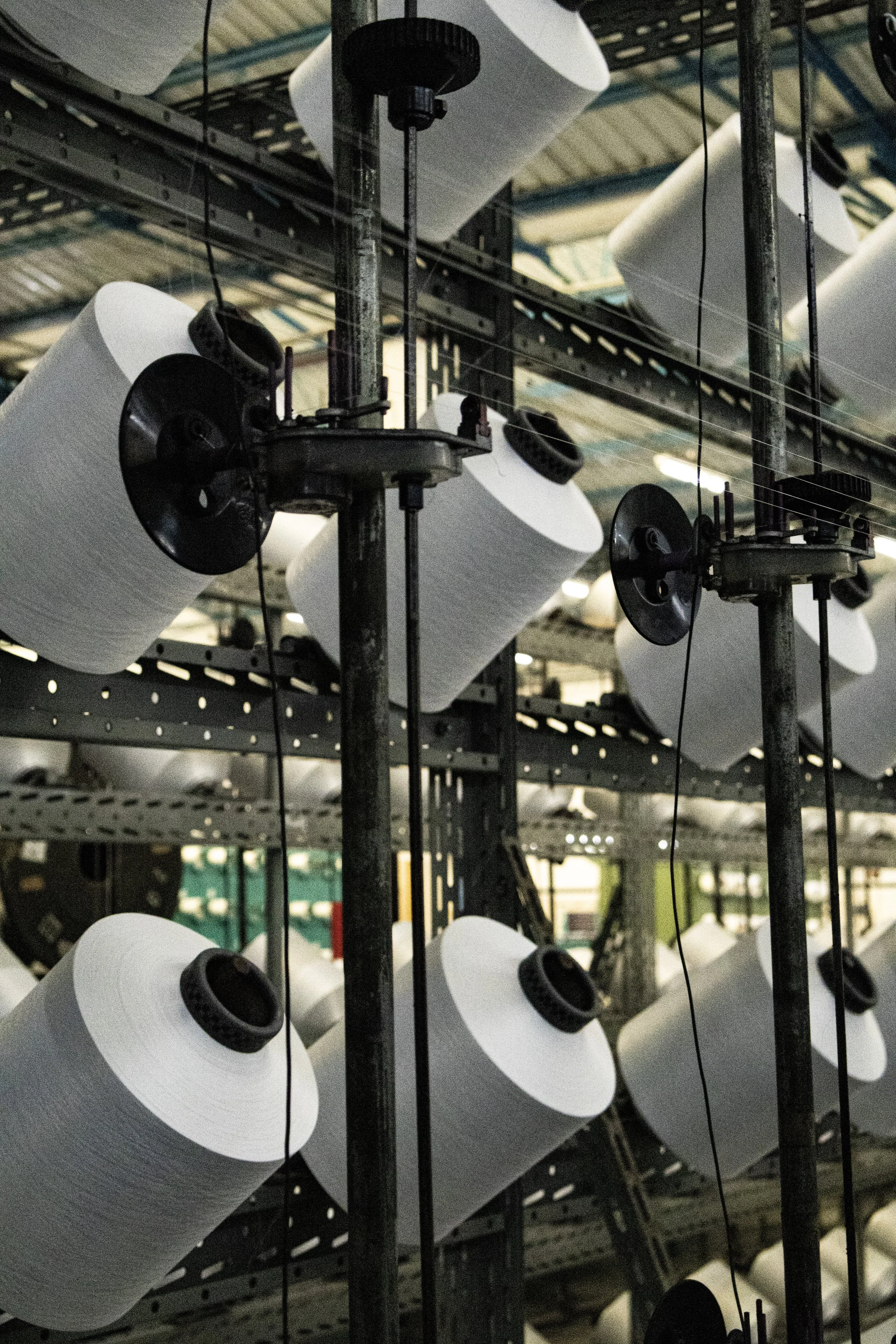 Fábricas de papel com rolos grandes de papel branco em uma estrutura metálica, possivelmente uma planta industrial de papel.