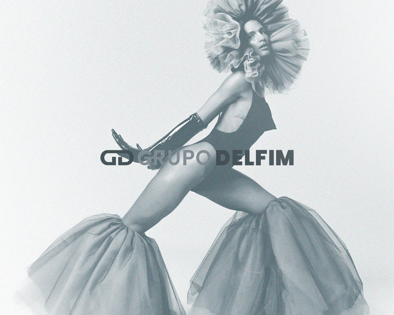 Imagem em tons de cinza de uma mulher com um vestido grande de tule, usando luvas longas e uma tiara de tecido em volta da cabeça, com o logo do Grupo Delfim sobreposto.