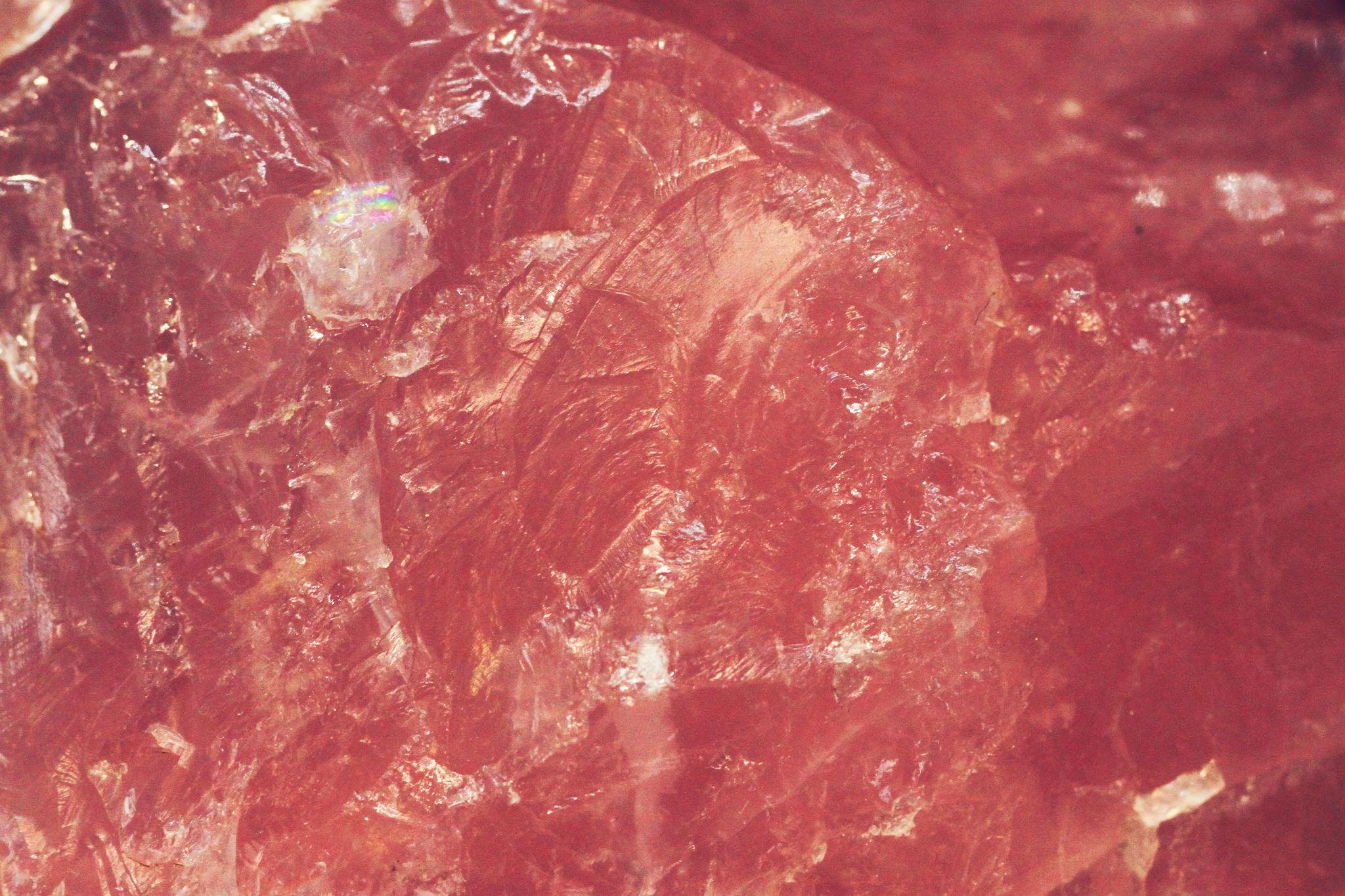 Close-up of a red, textured surface with shiny and rough areas.