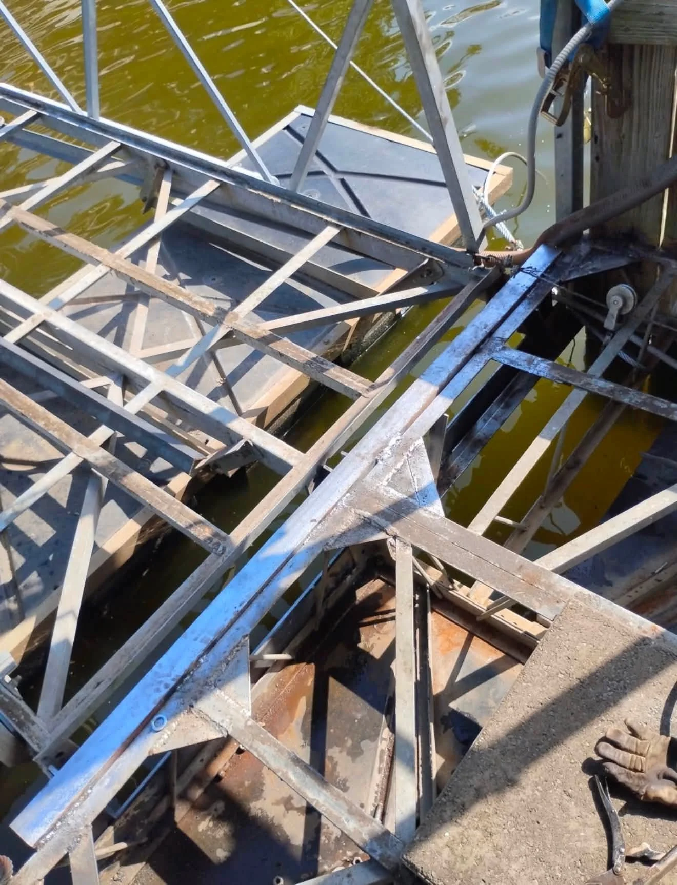 Metal framework and scaffolding structure near a body of water, with a hydraulic lift mechanism visible in the scene.