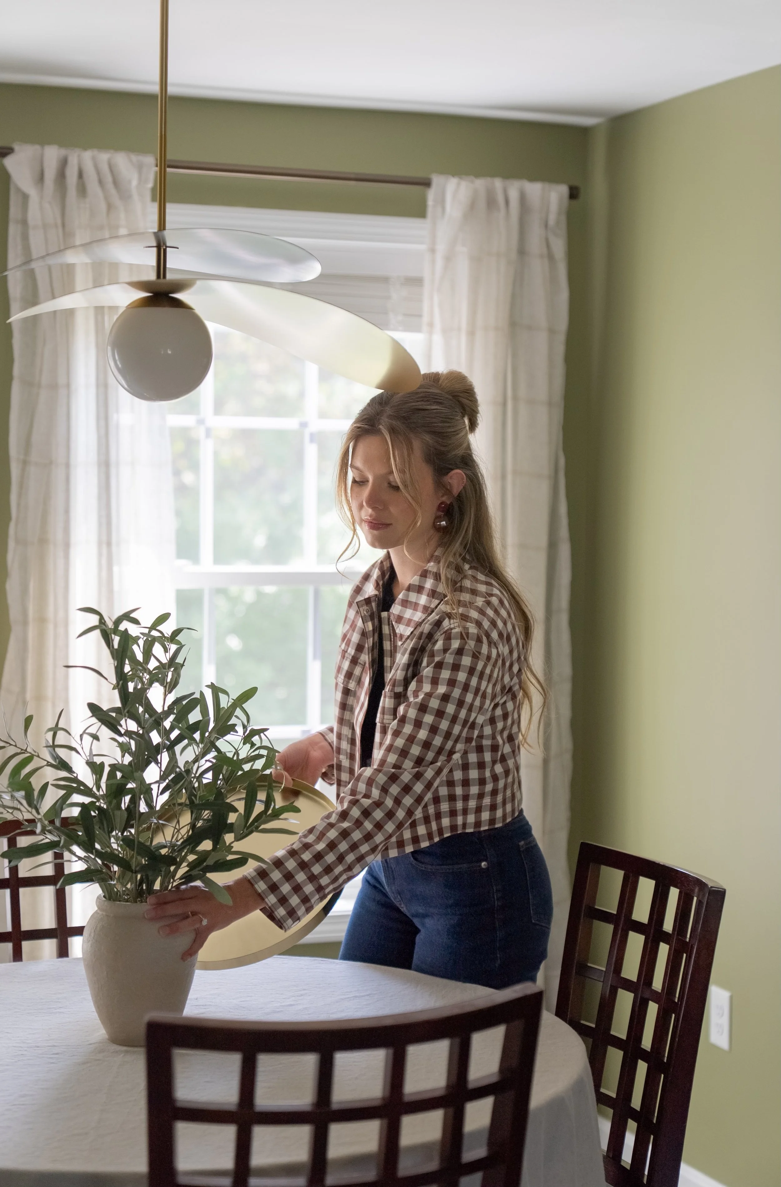 Arlyss arranging decor in a dining room for an interior styling client.