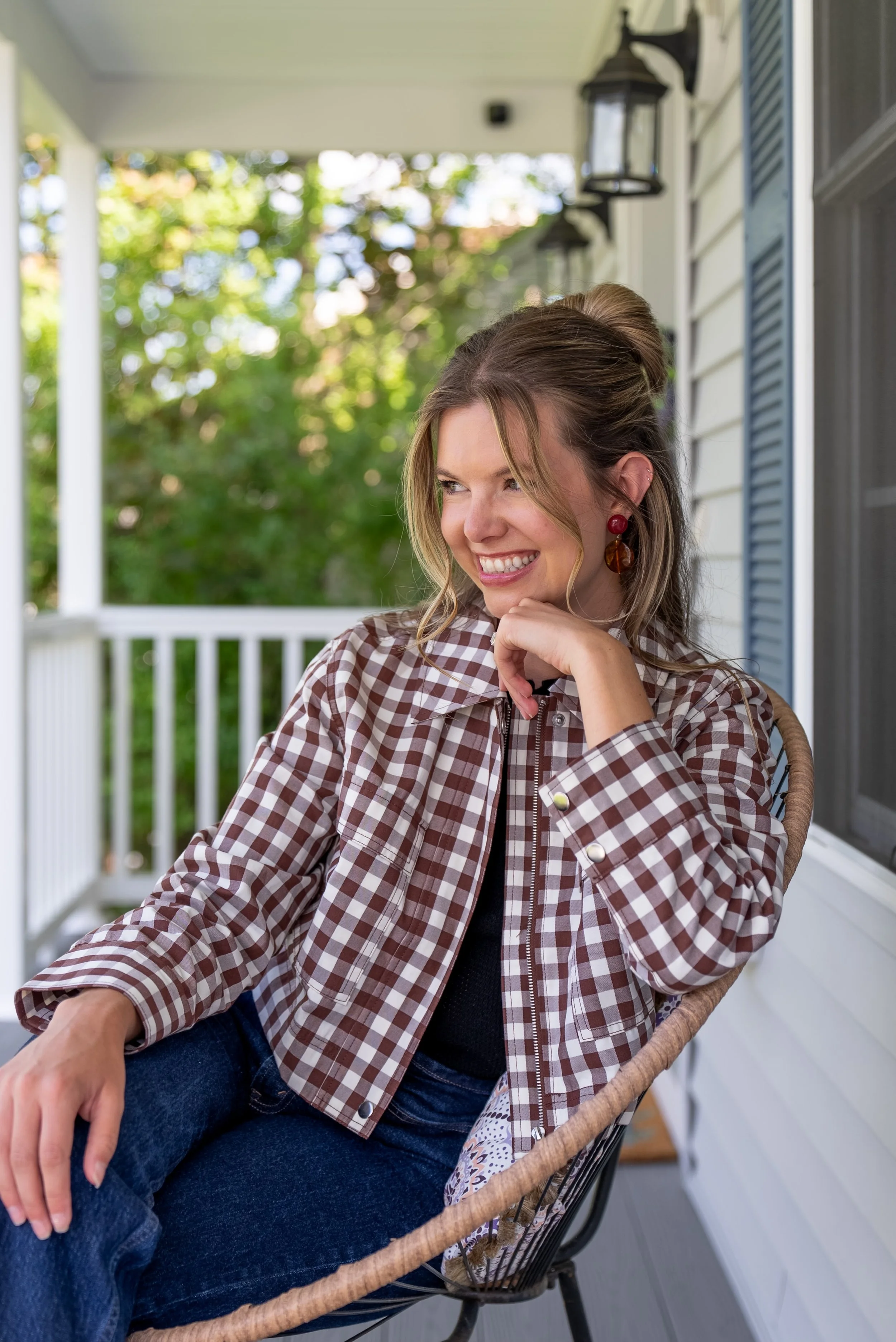 The owner of By Arlyss, Interior Styling, Arlyss sitting on the porch of a beautiful home. She is preparing for a styling consult for in person design.