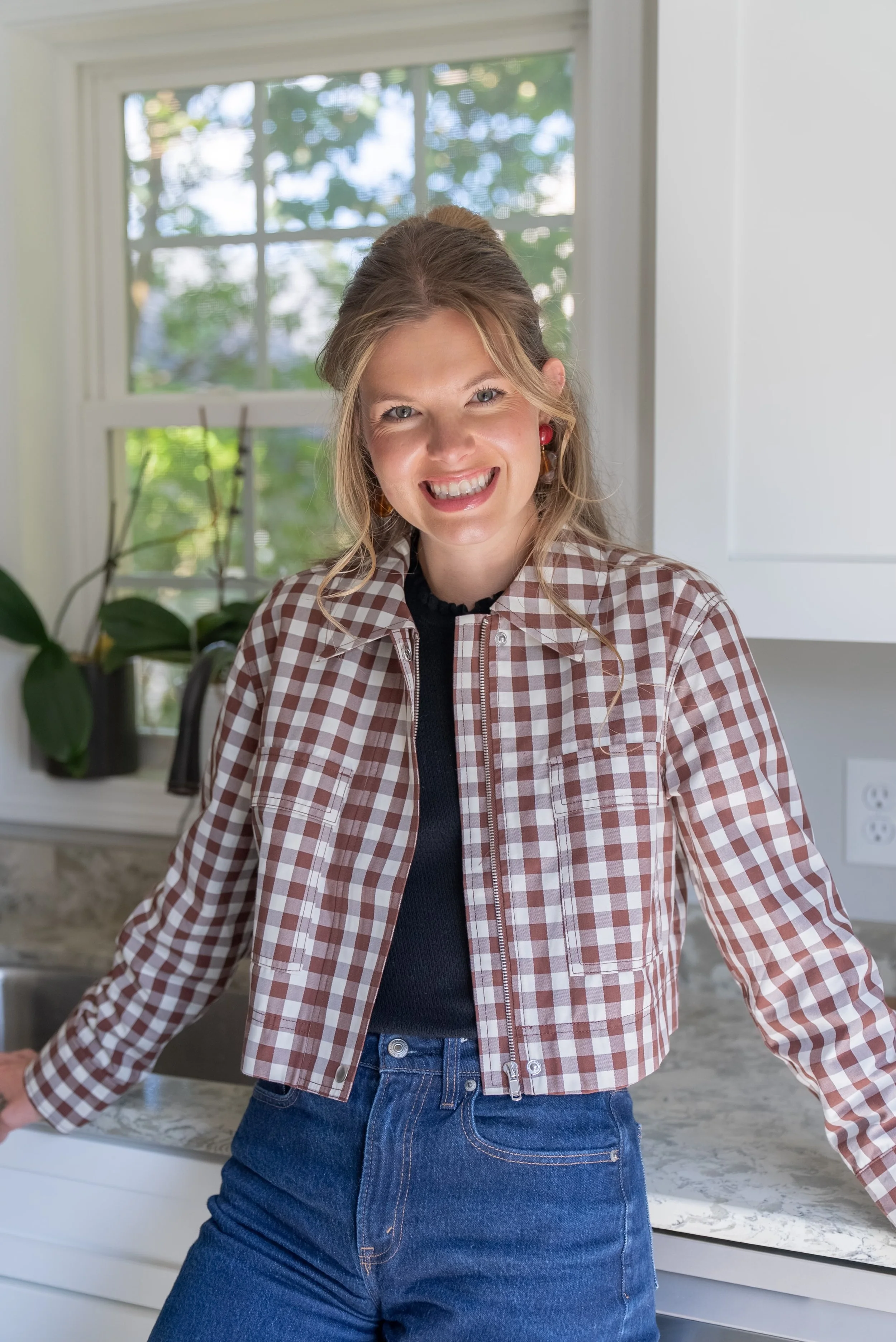 Arlyss standing in a neutral, organic modern kitchen styled with warm textures and natural light. By Arlyss Styled a beautiful space.