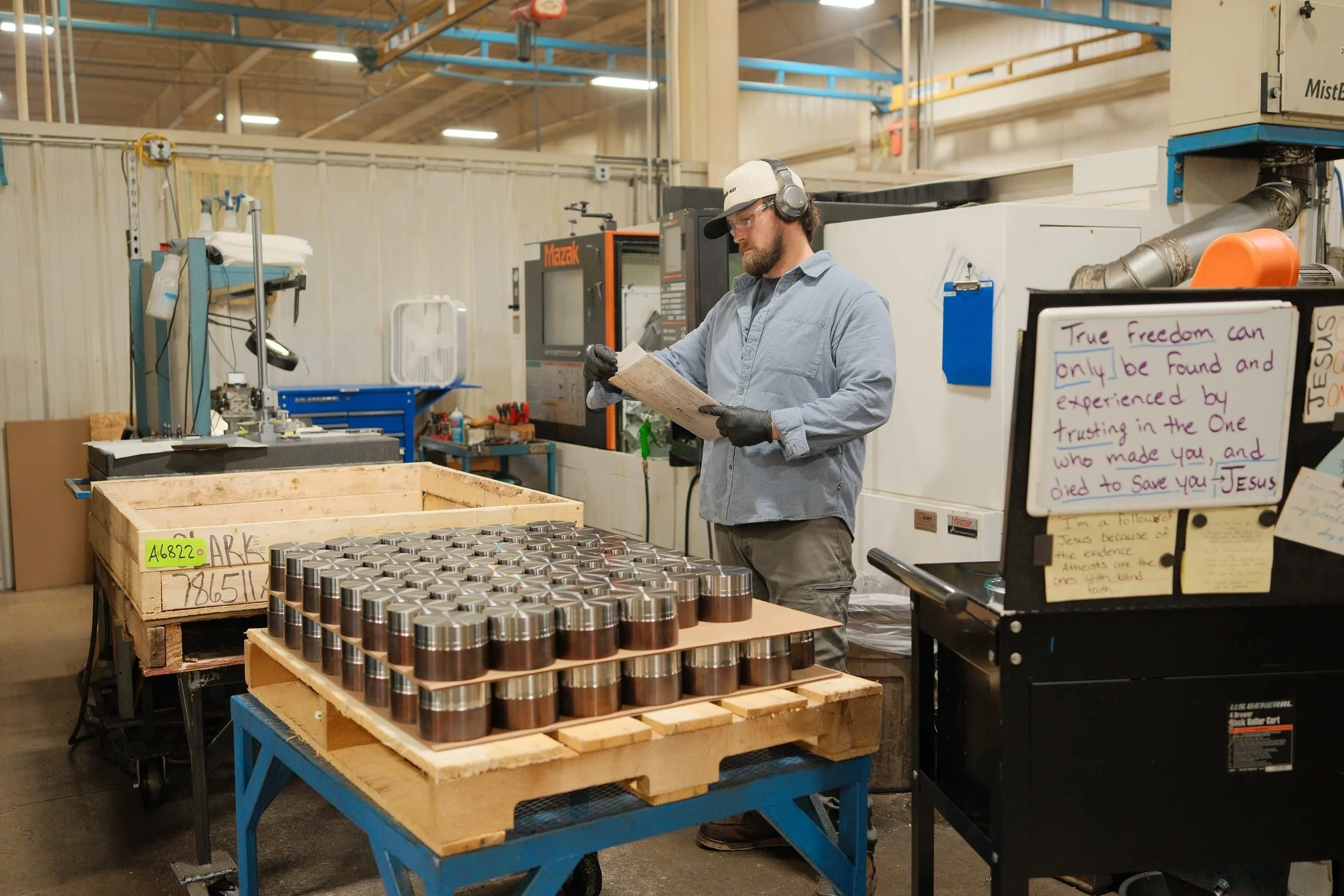Clark Manufacturing team member reviewing a production job beside machined components