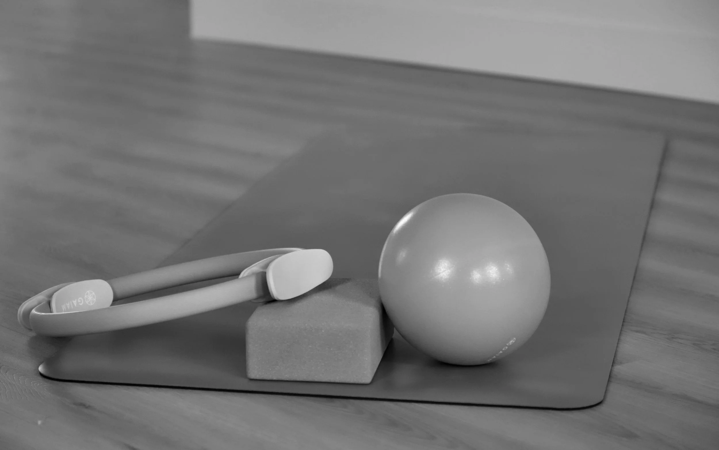 Black and white photo of a wooden tray holding a pair of chopsticks and a spherical object, with a blurred background.