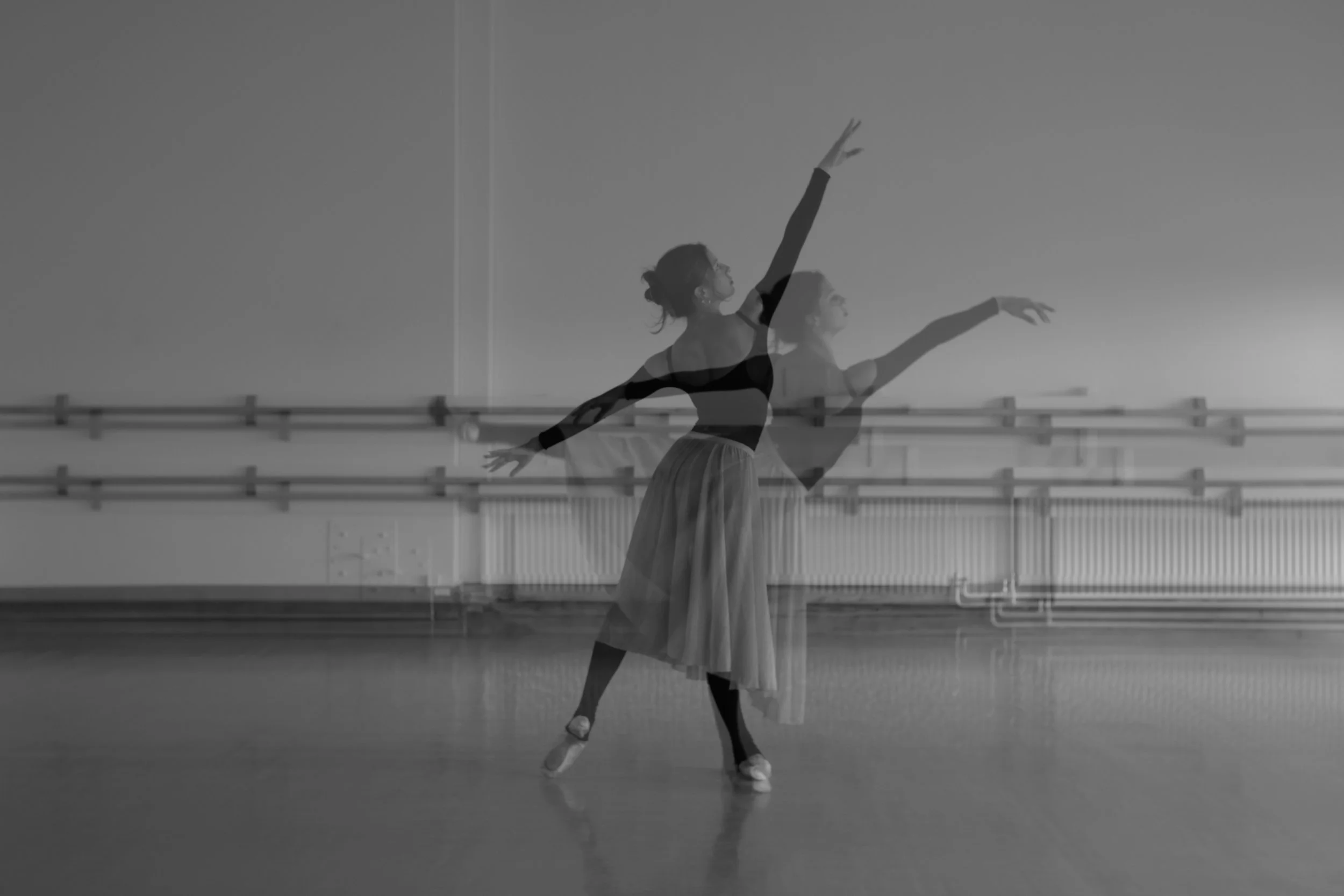 A ballet dancer practicing in a dance studio, captured in motion with multiple exposure effect, wearing a black leotard and a flowy skirt, with ballet barre in the background.