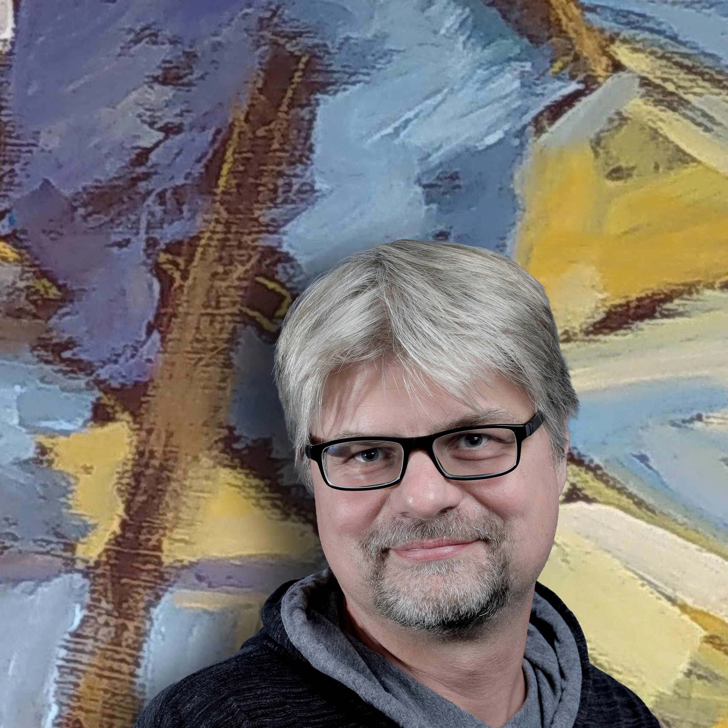 Nahaufnahme eines Mannes mit grauen Haaren und Brille vor einer bunten Wand. Die oberen Gesichtspartien sind sichtbar.