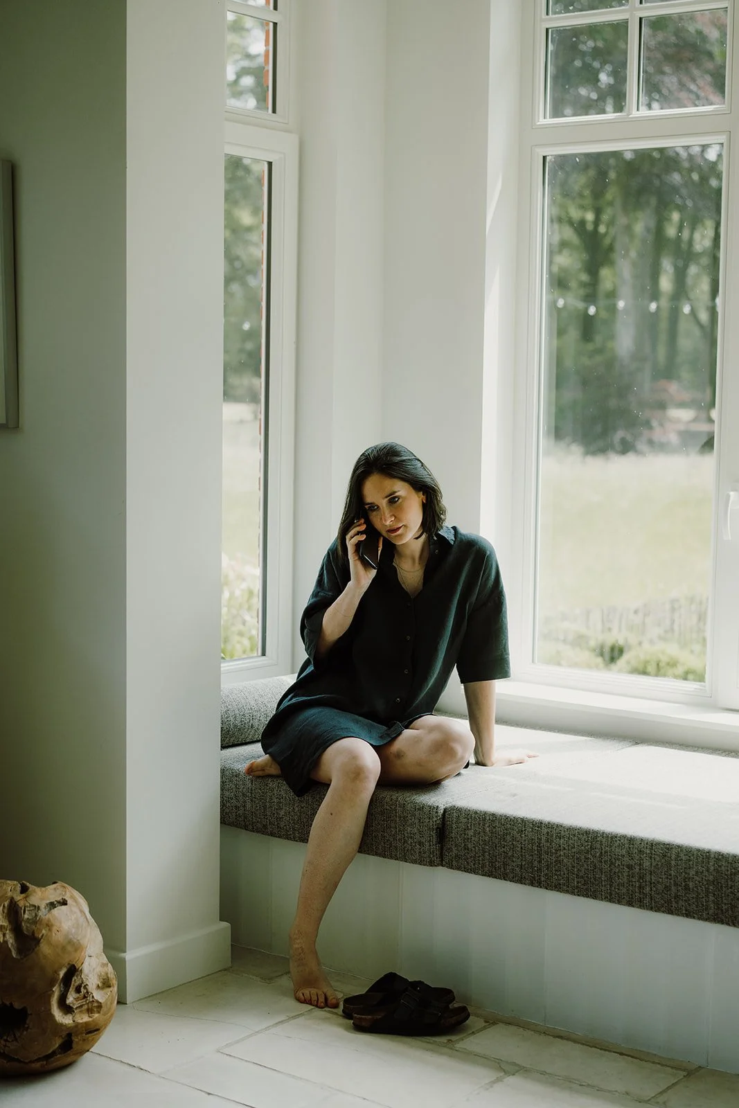bellende zangeres op daybed in erker, zittend