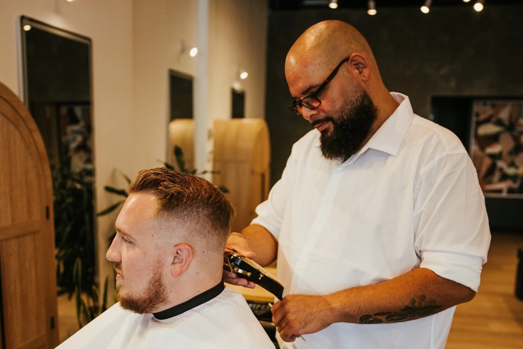 Barber using clippers to finish up a high tapered fade