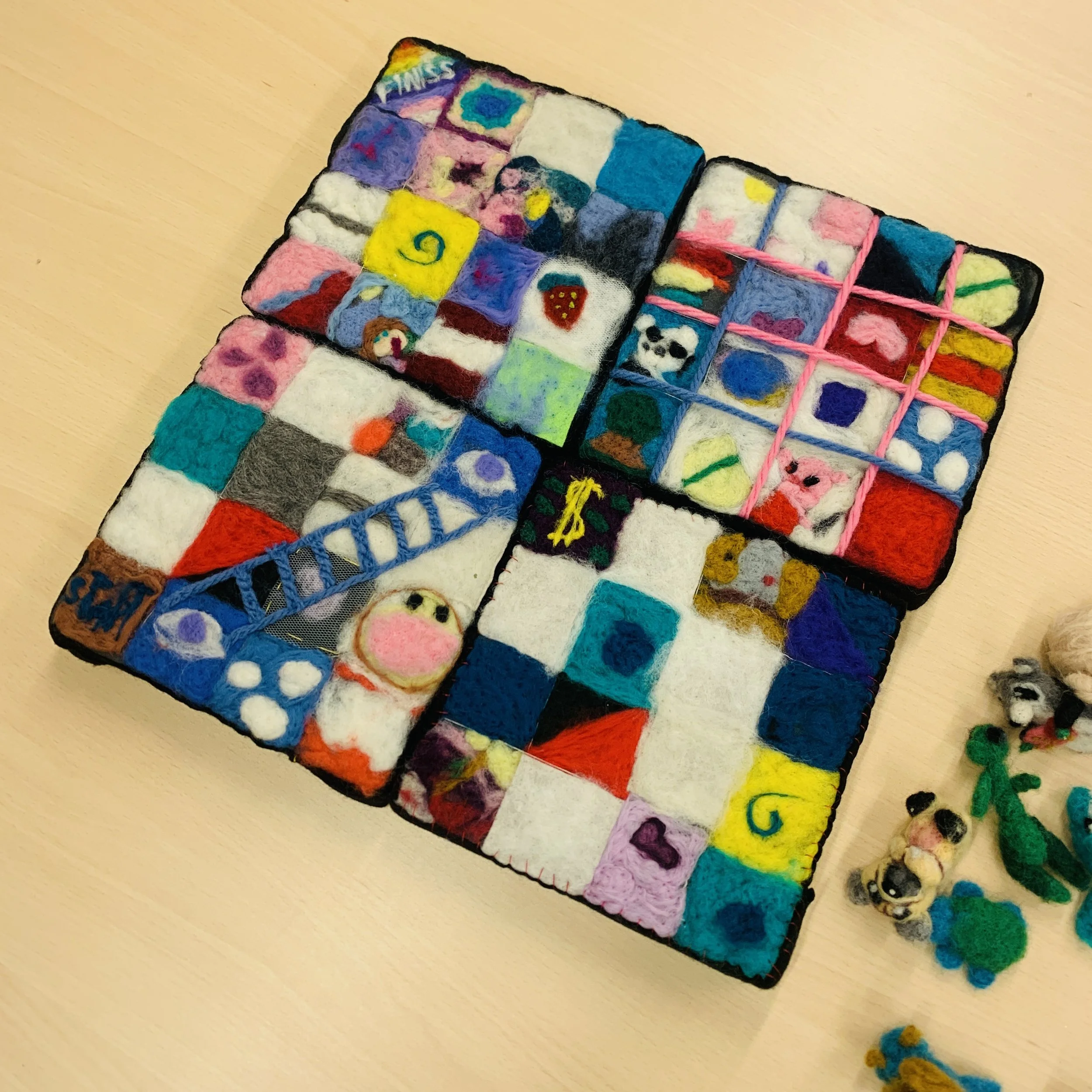 A handmade felt and fabric art piece ''Cirks'' with colorful embroidered and felted images arranged in a grid pattern on a black-bordered surface.