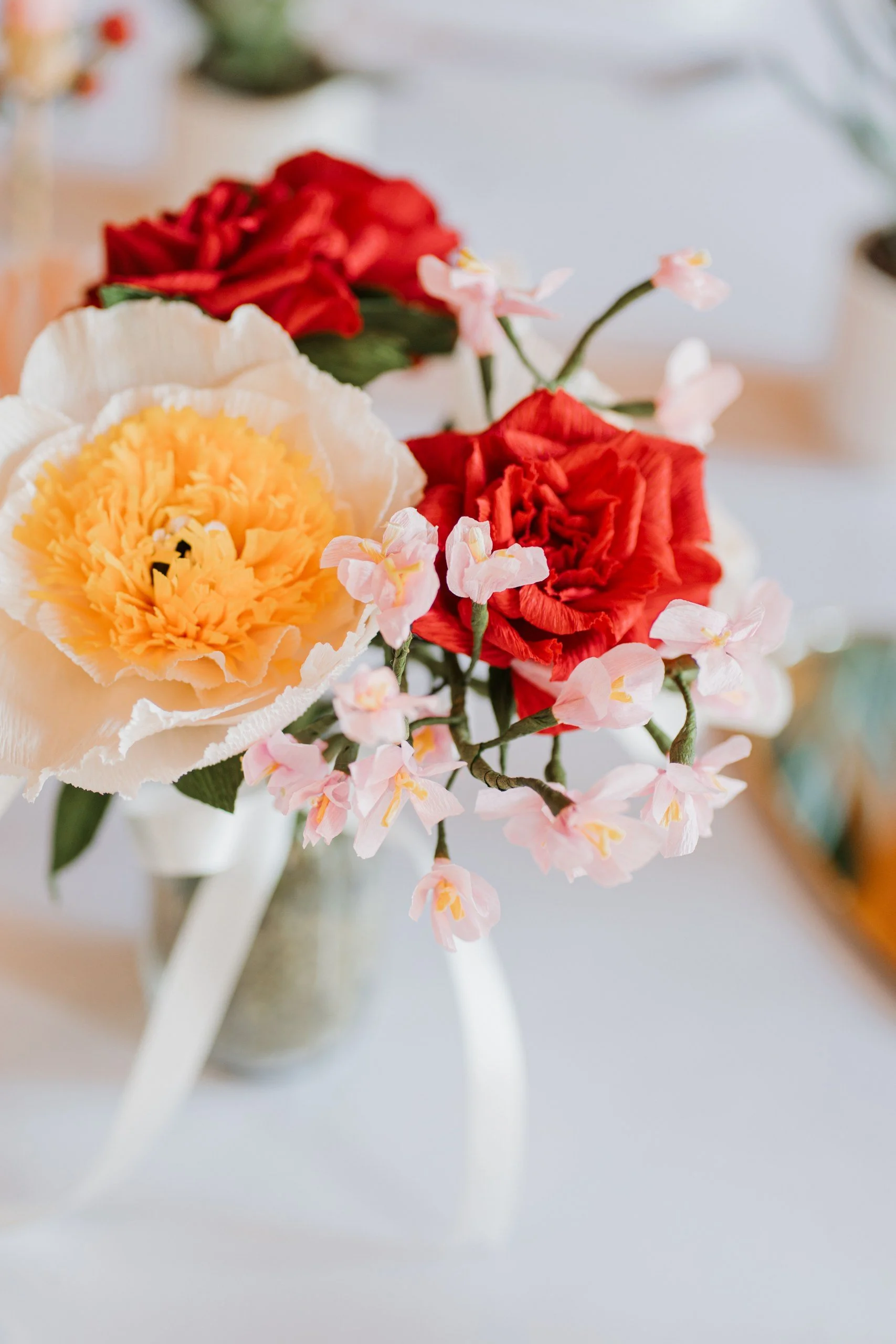 Close-up of a bouquet with cream, red, and pink flowers in a white vase.