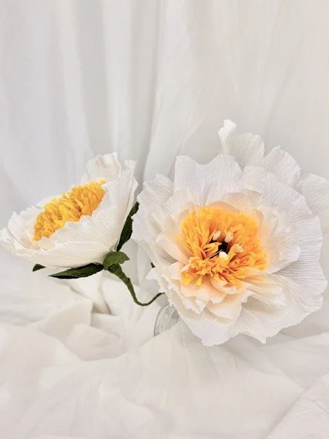 Artificial white and yellow poppy flowers in a white background.