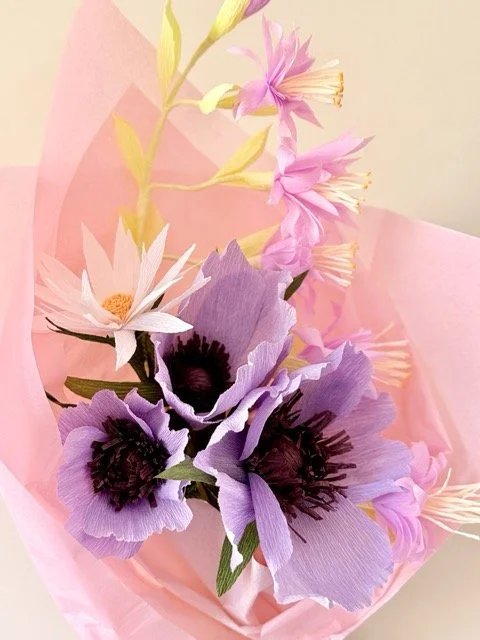 Artificial pink, purple, white, and yellow flowers wrapped in pink paper