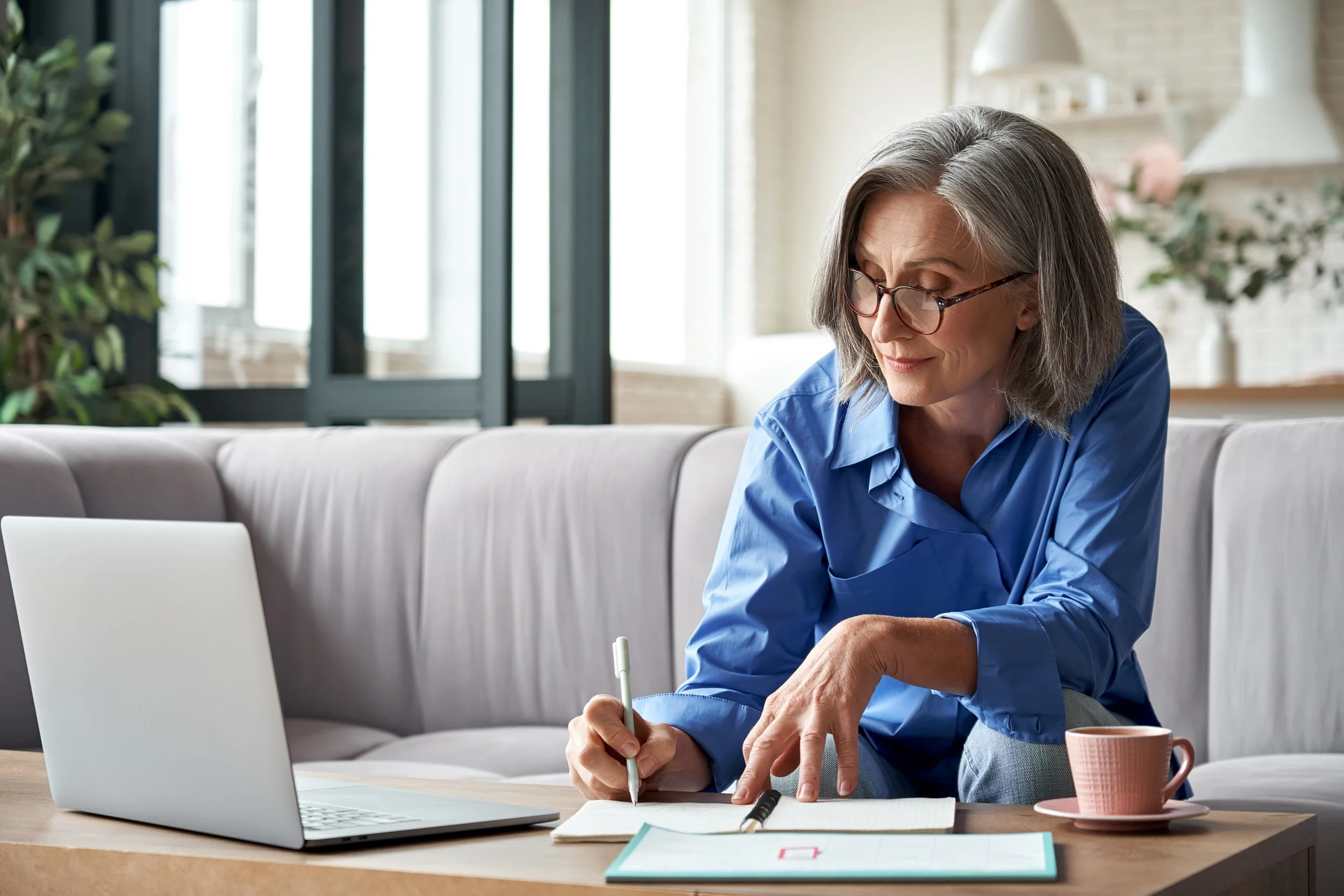 Older woman working on paperwork in her home.