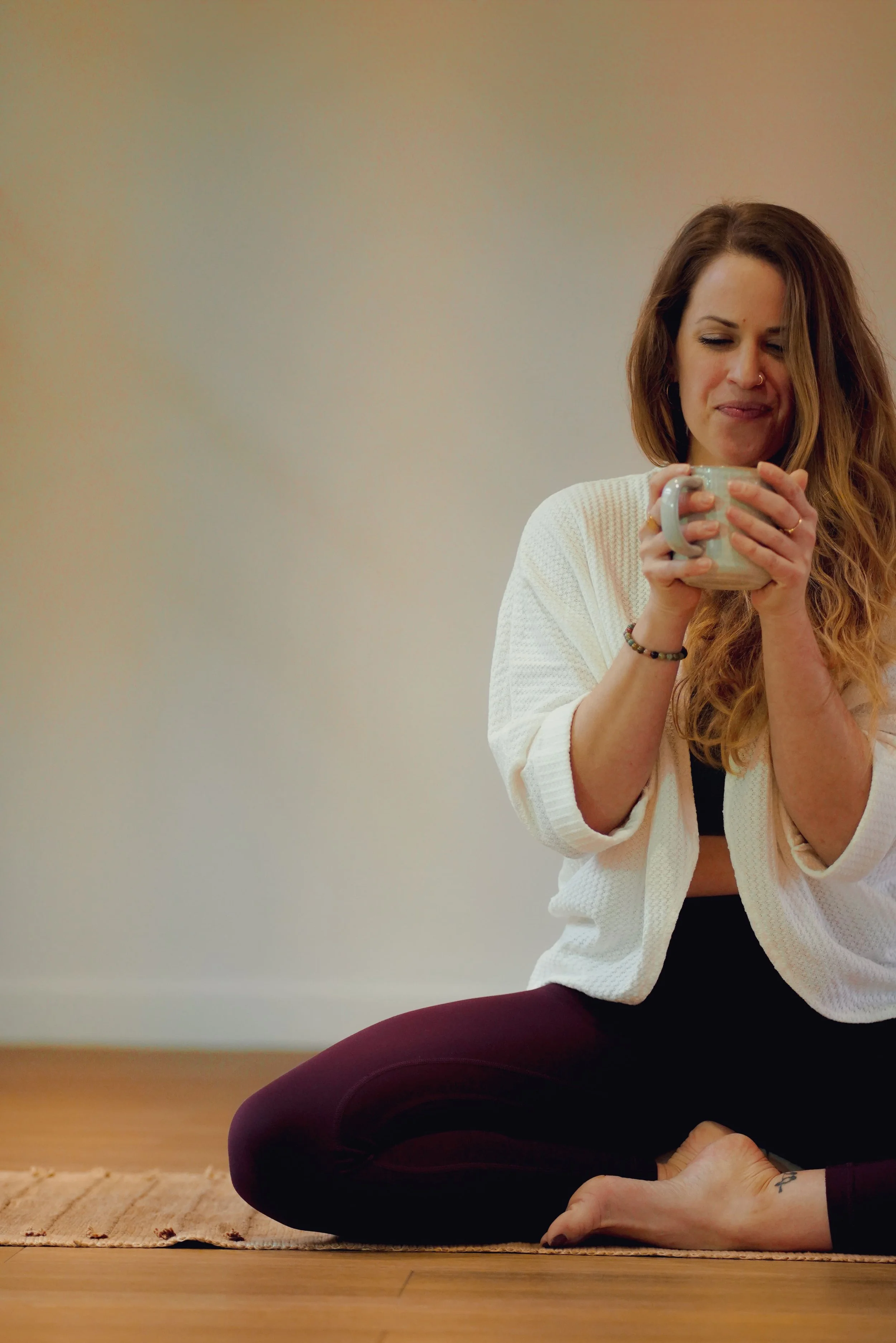 Laura, professeure de yoga assise en position de lotus sur un tapis