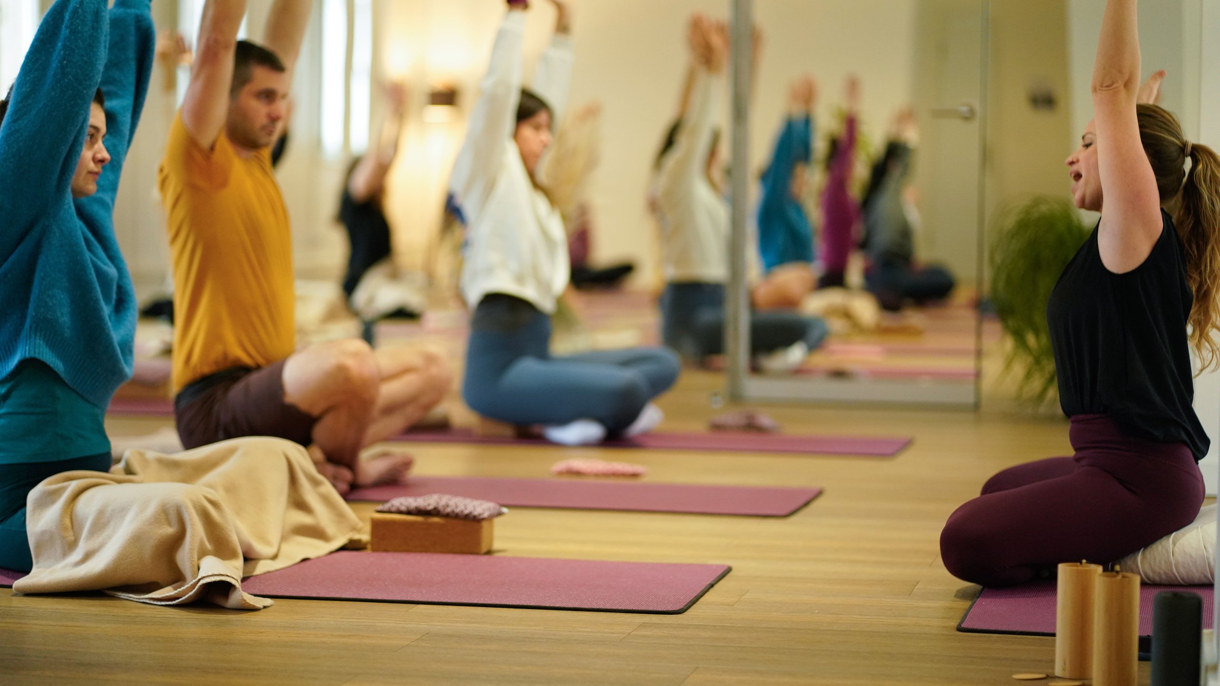 Cours de yoga avec plusieurs pratiquants en position en pleine respiration dans une salle de yoga à Besançon