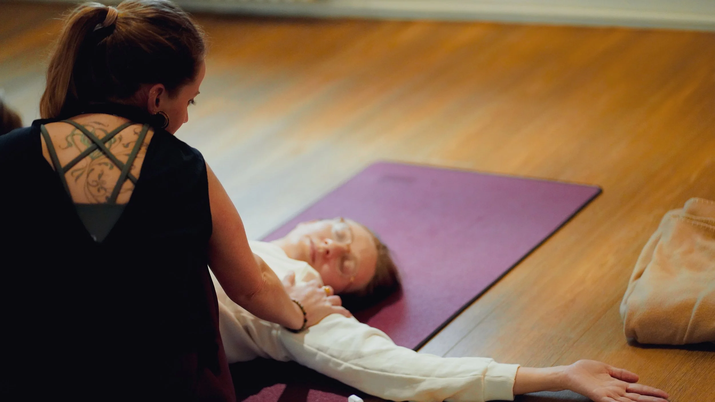 Une femme aide une personne âgée à faire de l'exercice sur un tapis de yoga dans une salle