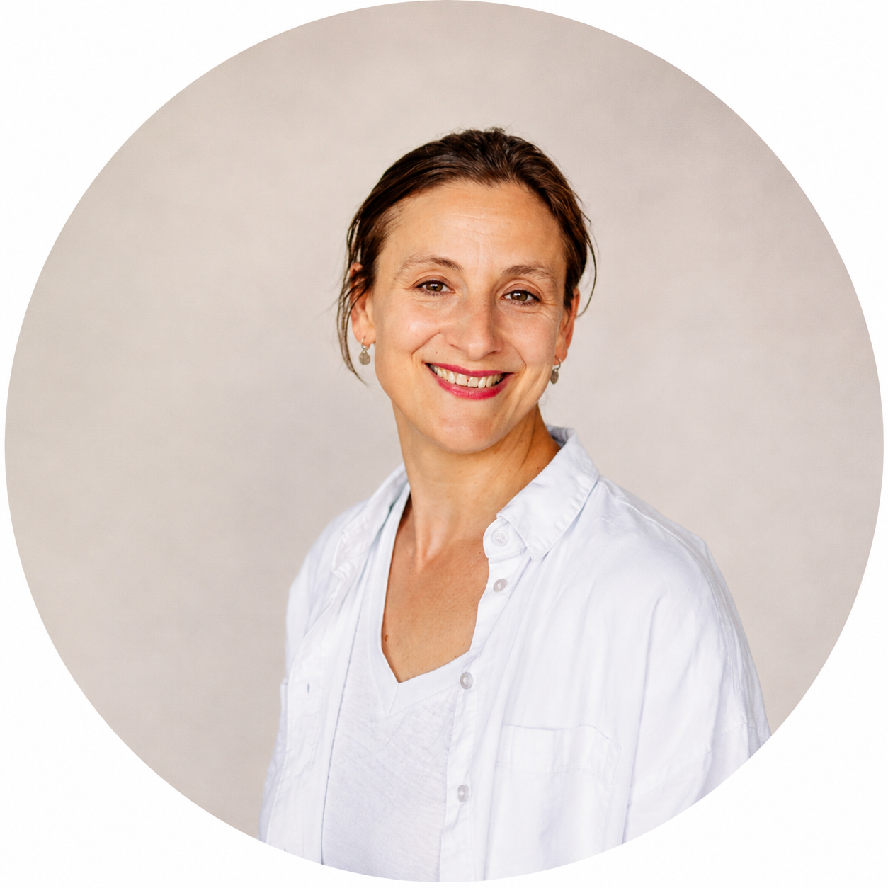 Porträt von Dr. Janine Reinhard mit braunen Haaren, die zu einem Zopf zurückgebunden sind und einer weißen Bluse vor neutralem Hintergrund.