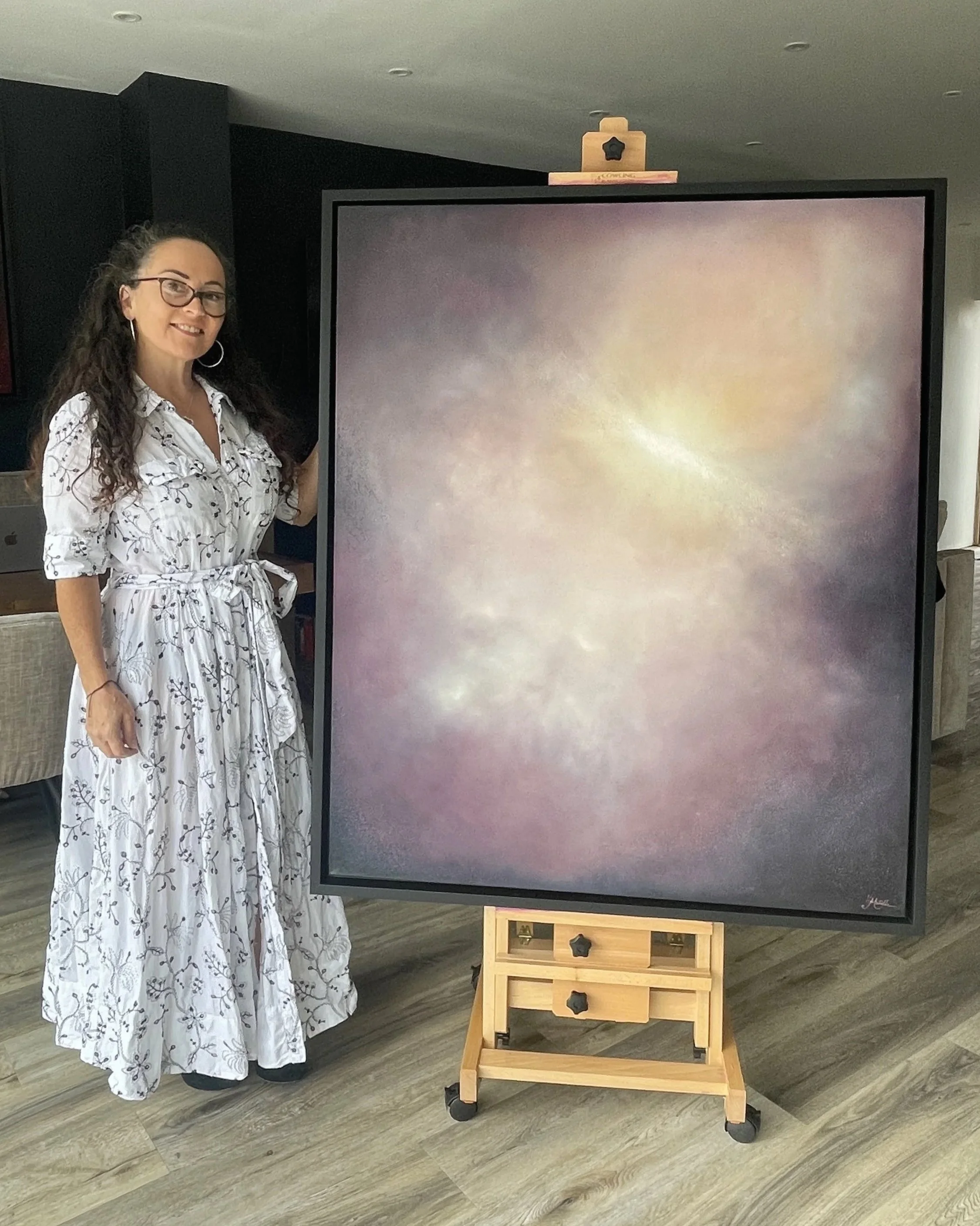 Artist Mechelle Tebbs standing beside her atmospheric abstract oil painting, Attunement.