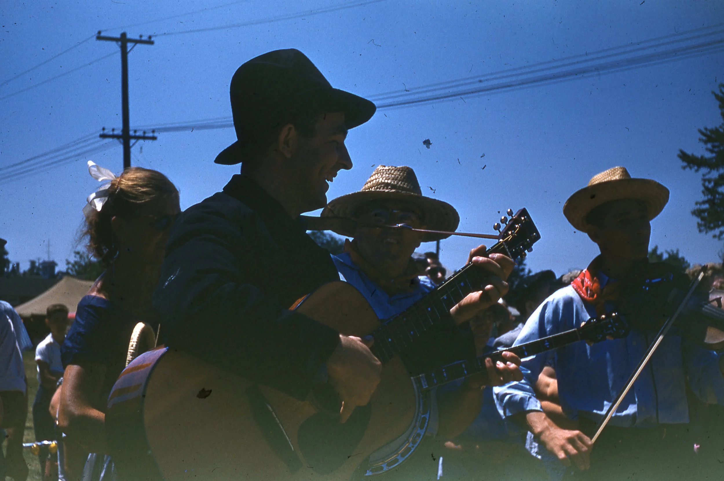 Dr. Bill Frey playing guitar with band outdoors.