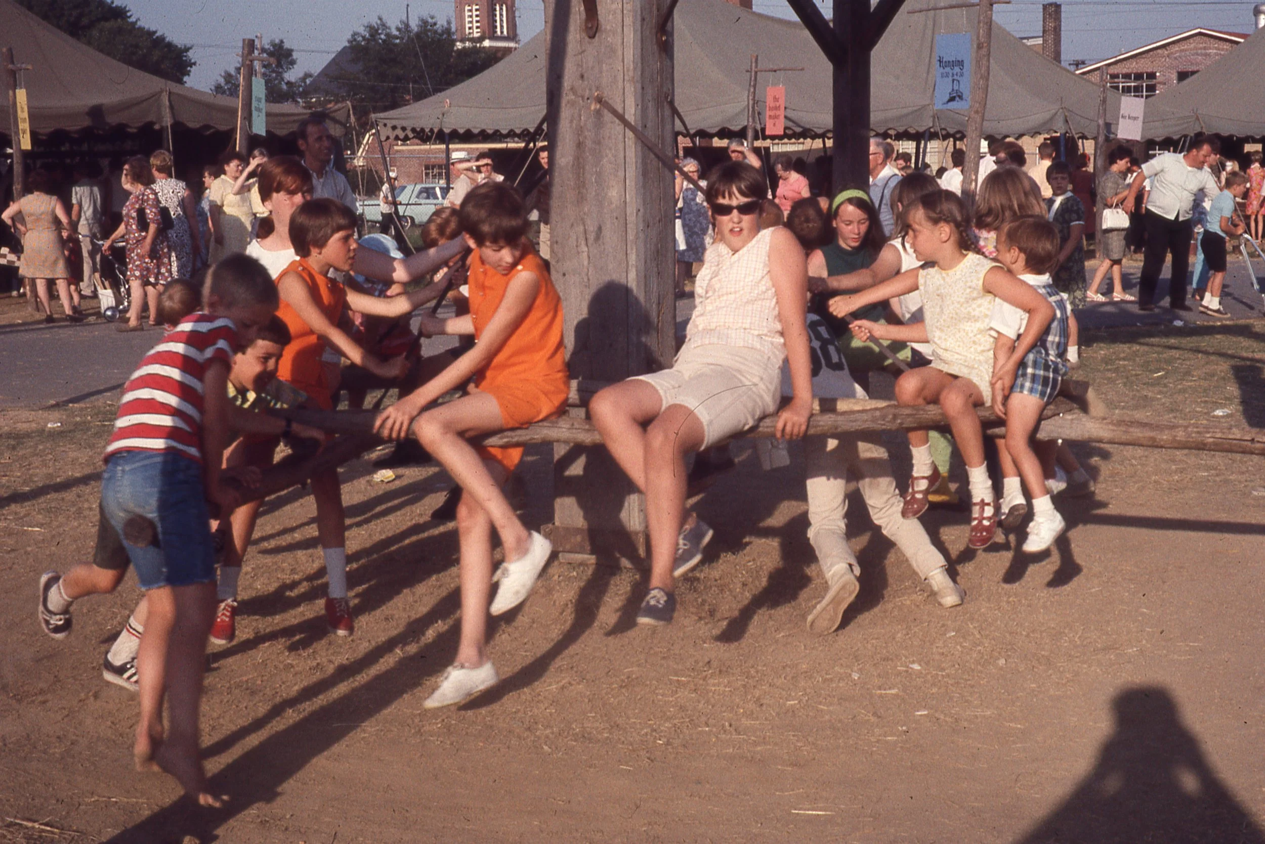 Group of children sitting on large wooden horse-turned mill.