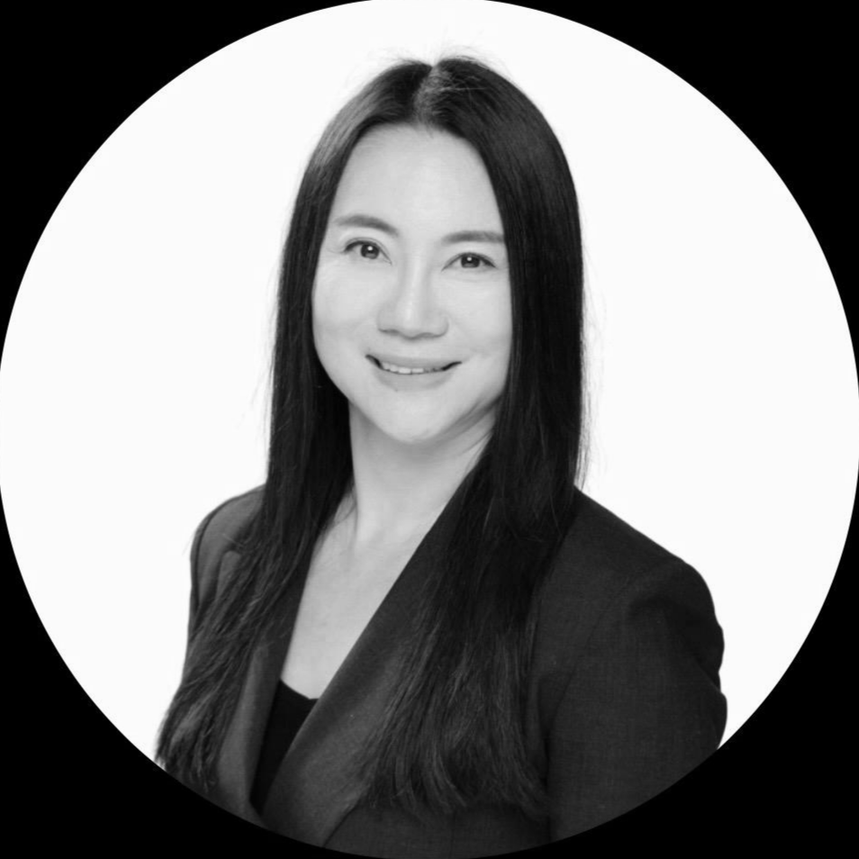 Black-and-white professional portrait of a woman with long, dark hair, smiling and wearing a blazer.