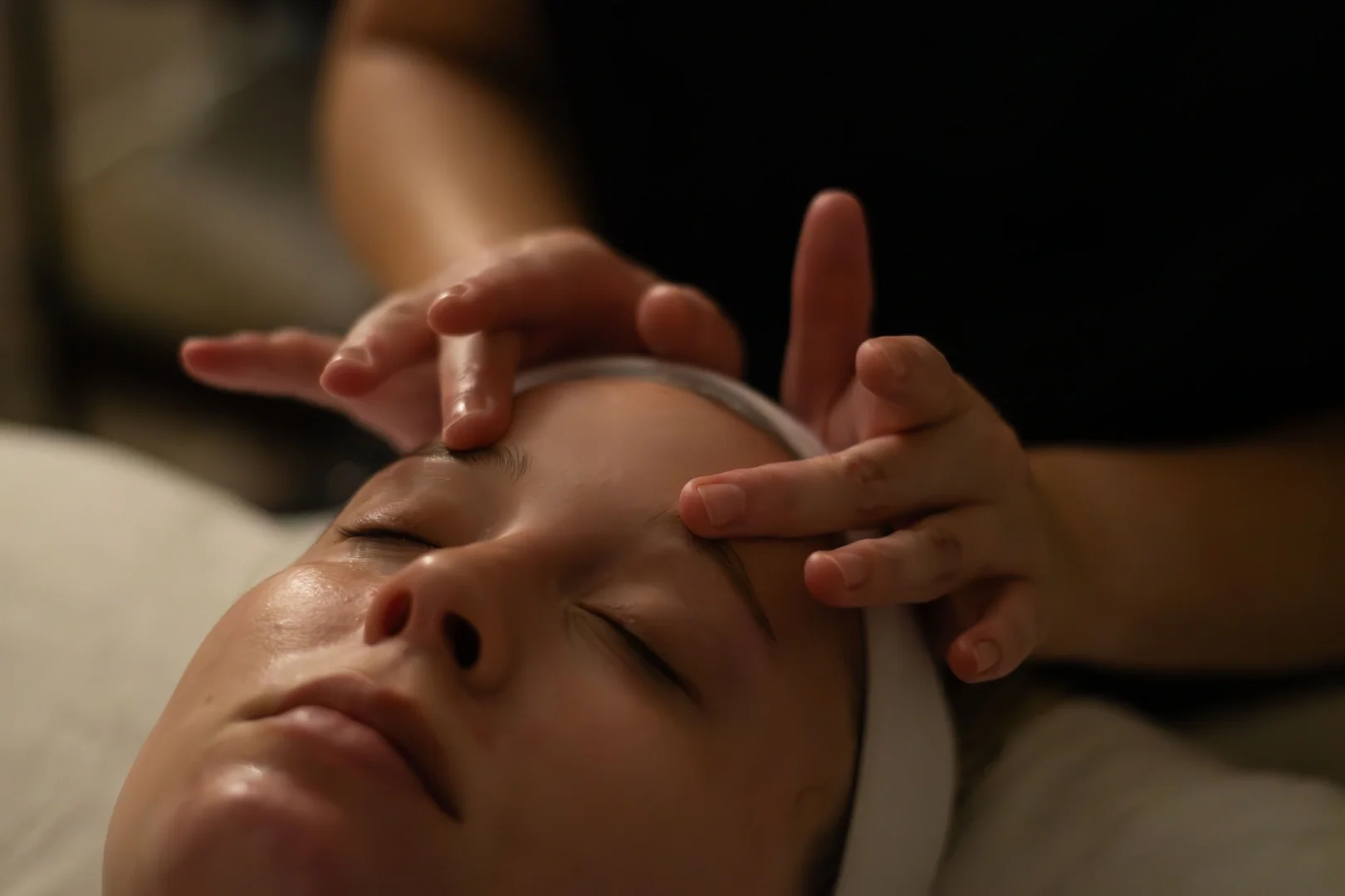 Person receiving a facial massage or skincare treatment, with closed eyes and relaxed expression.