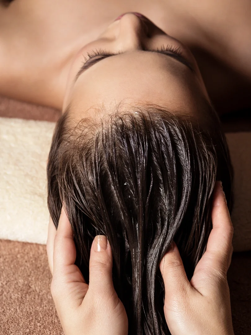 Person receiving a scalp massage with shampoo, lying on a towel.