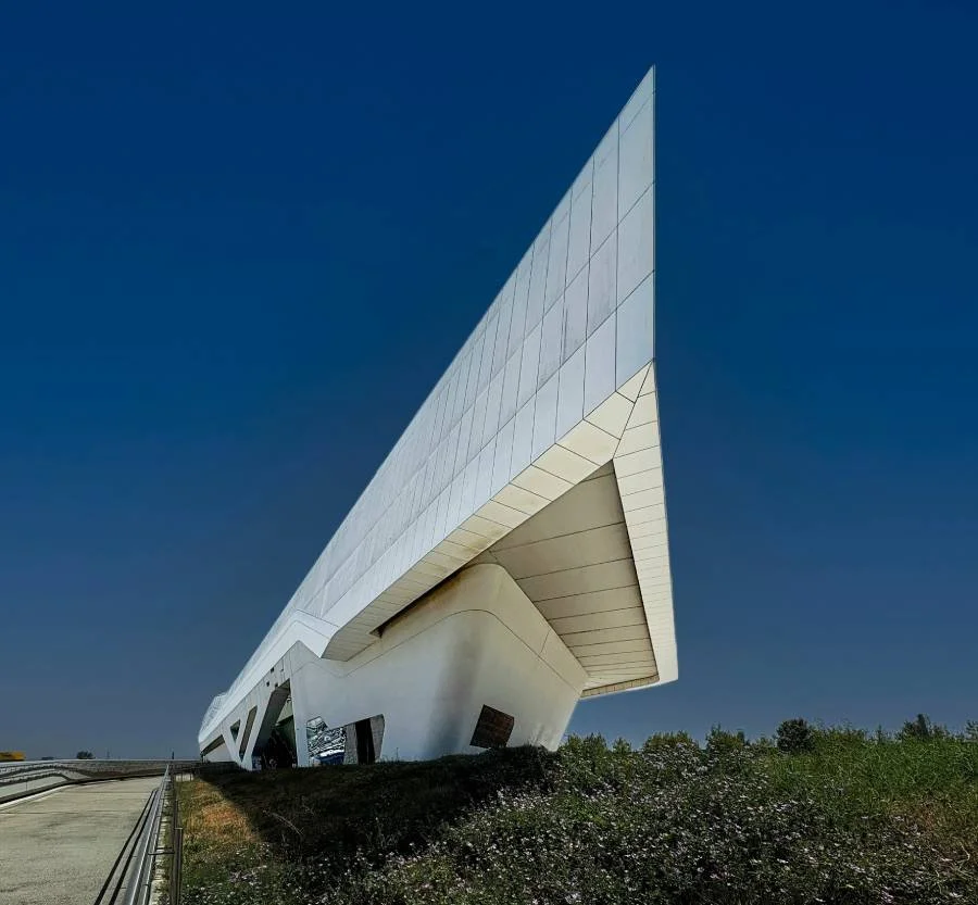 Moderne witte architectuur van een futuristisch gebouw onder een heldere blauwe hemel.