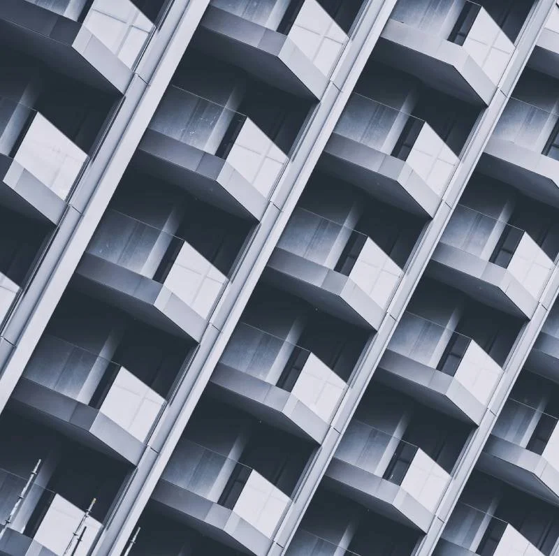Uitzicht op een modern appartementencomplex met meerdere balkons en grote ramen, afgebeeld in een diagonale hoek.